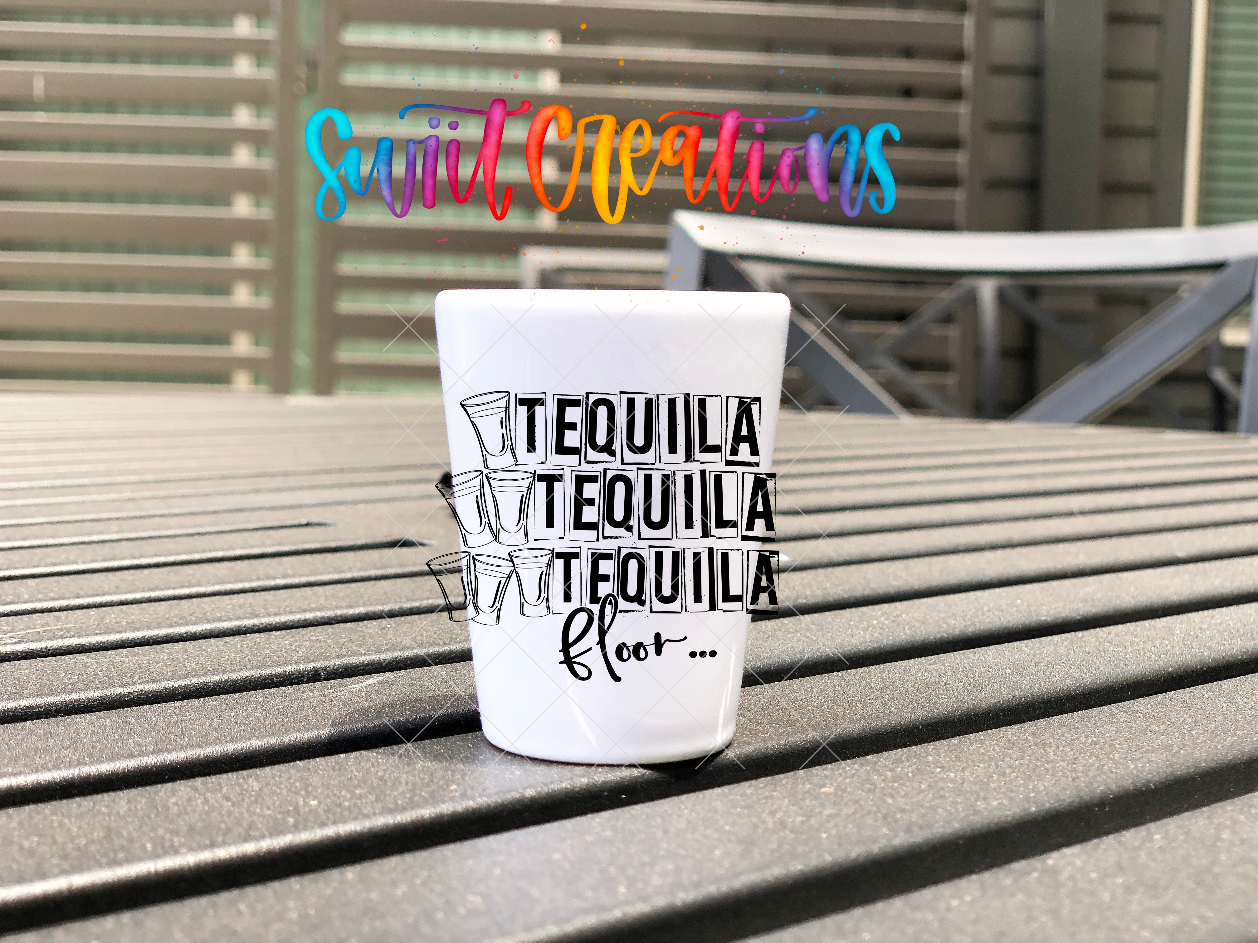 A white cup with the text "TEQUILA TEQUILA TEQUILA" printed on it, sitting on a wooden surface.