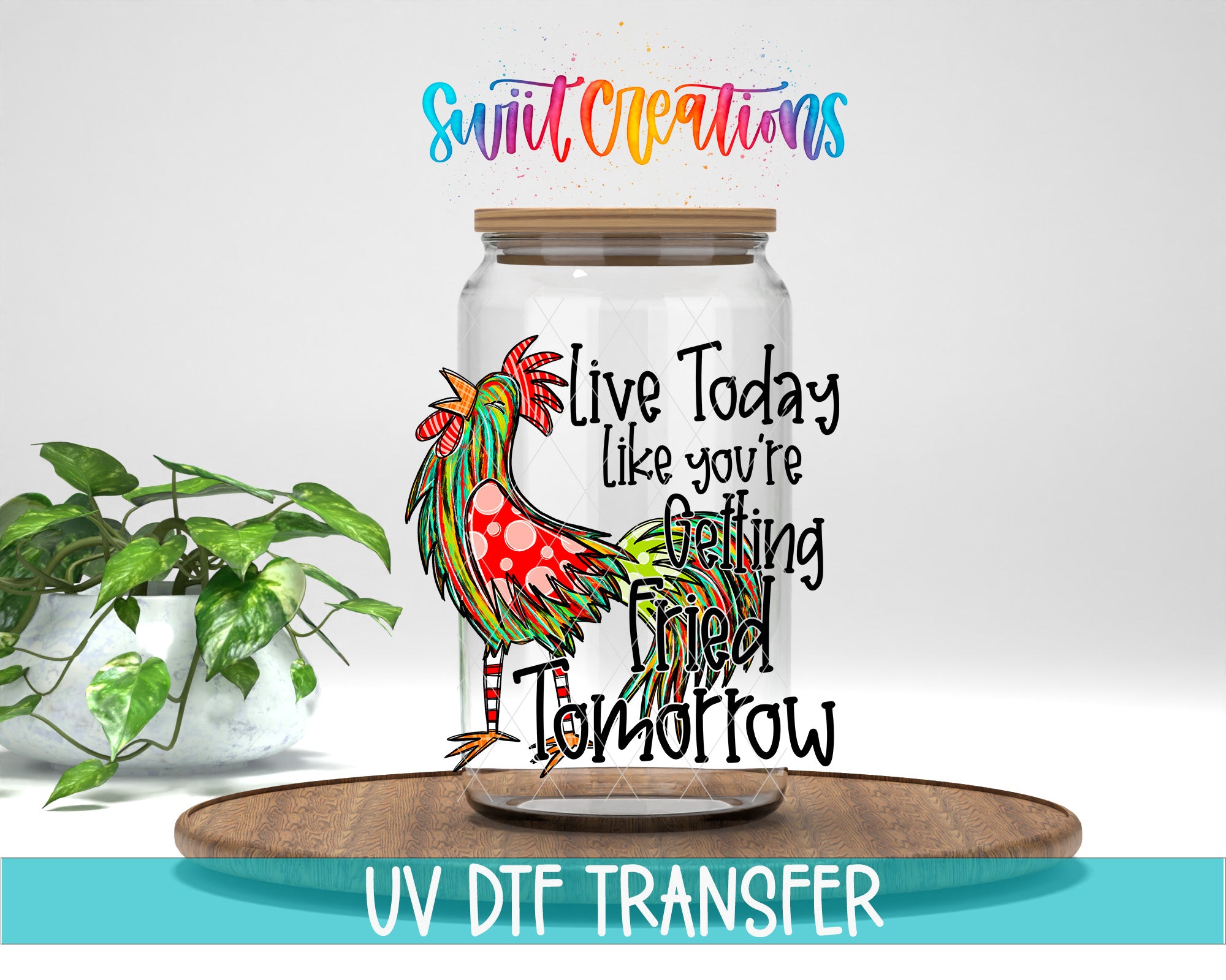 A glass jar with a colorful rooster design on it, along with the text "Live Today like you're getting fried tomorrow" printed on it. The jar is placed on a wooden surface, and there is a potted plant in the background.