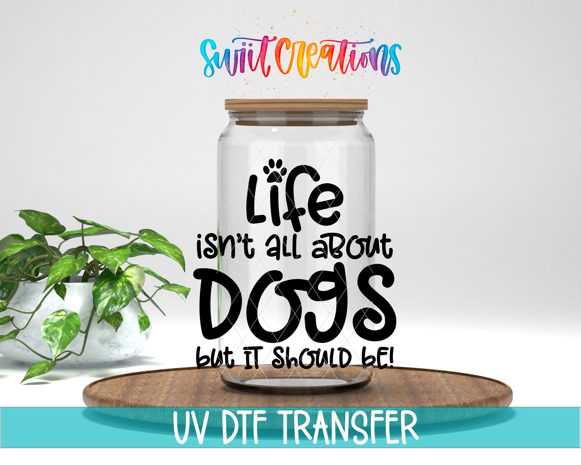 a clear glass jar with a wooden lid, placed on a wooden tray. The jar has a label with the text "Life isn't all about dogs but it should be!" written on it. In the background, there is a potted plant. The image also includes text that says "Swit Creations" and "UV Dtf Transfer".
