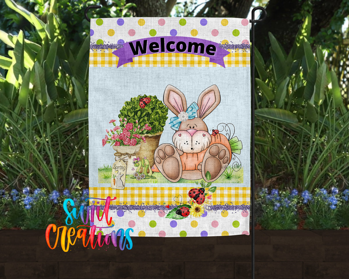 A colorful welcome sign featuring a cartoon rabbit sitting in a pot of flowers, surrounded by greenery and flowers.