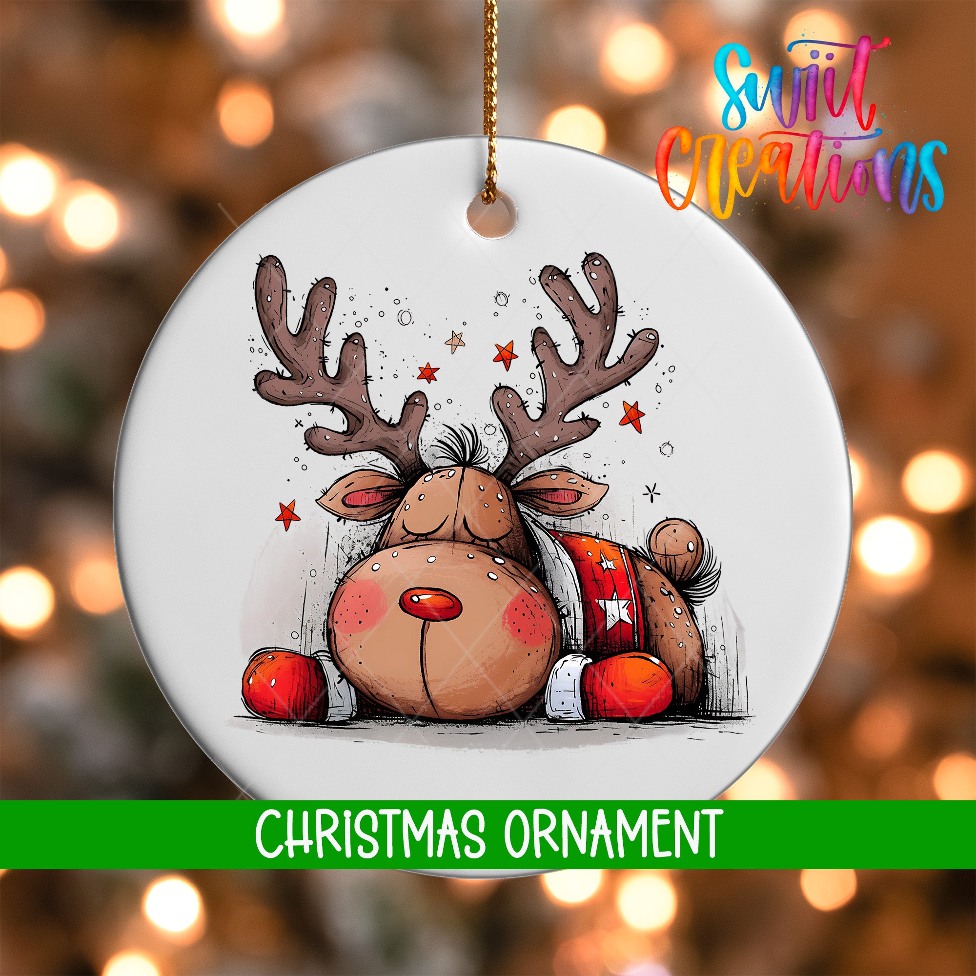 A white Christmas ornament featuring a cartoon reindeer with antlers and a red bow tie, surrounded by stars, against a blurred background of Christmas lights.
