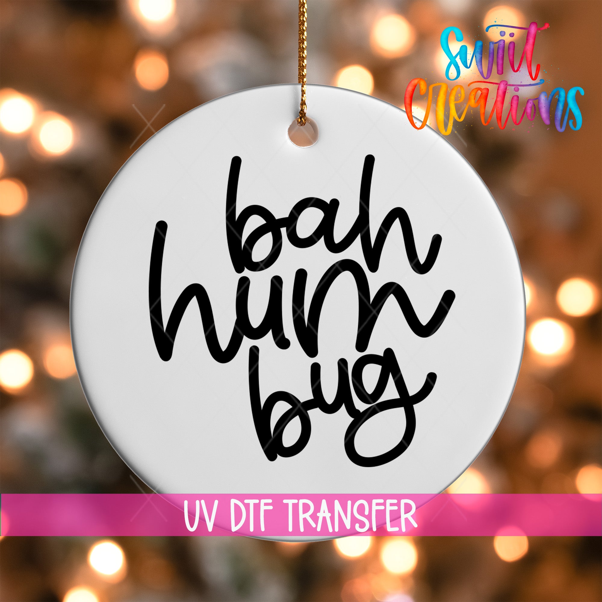 A white circular ornament with the text "bah hum bug" written on it, hanging against a background of colorful lights.