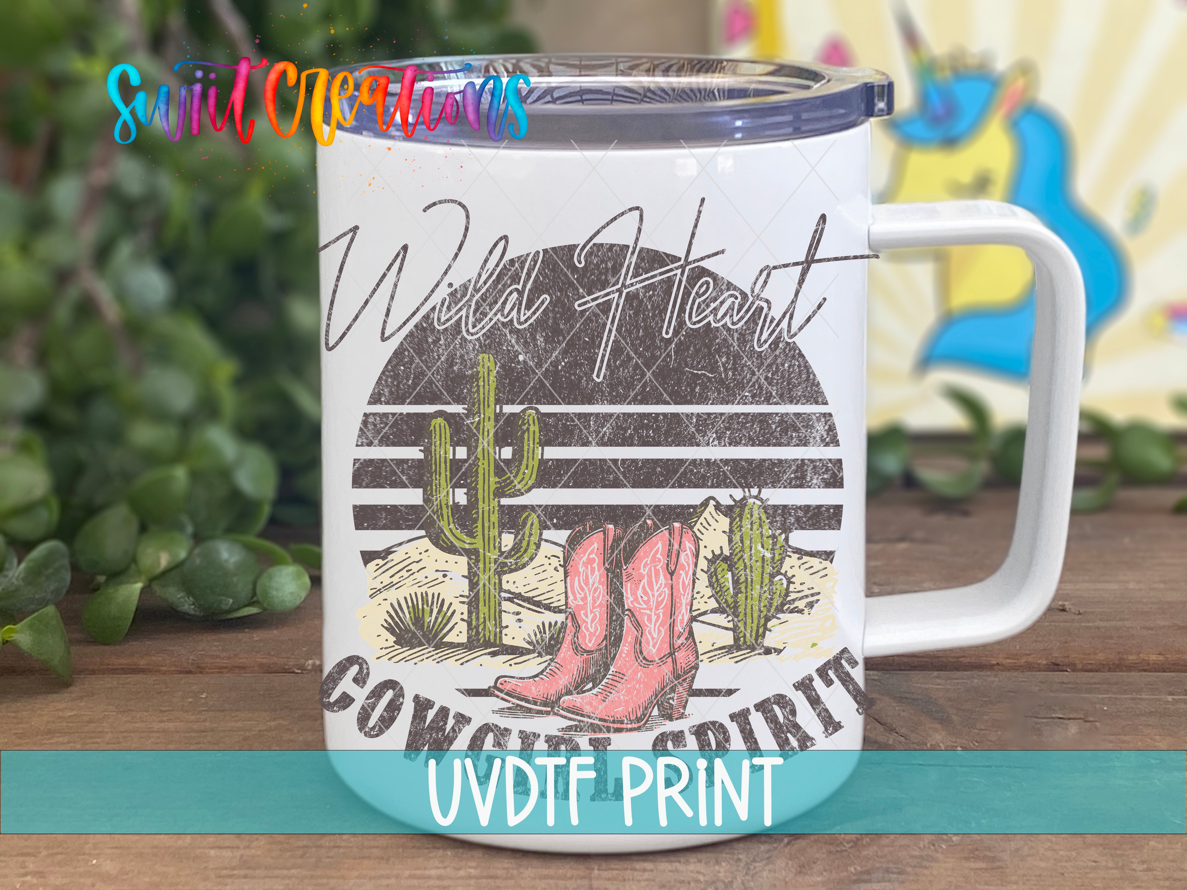 A white mug with a graphic design featuring a cactus, cowboy boots, and the text "Wild Heart" printed on it.