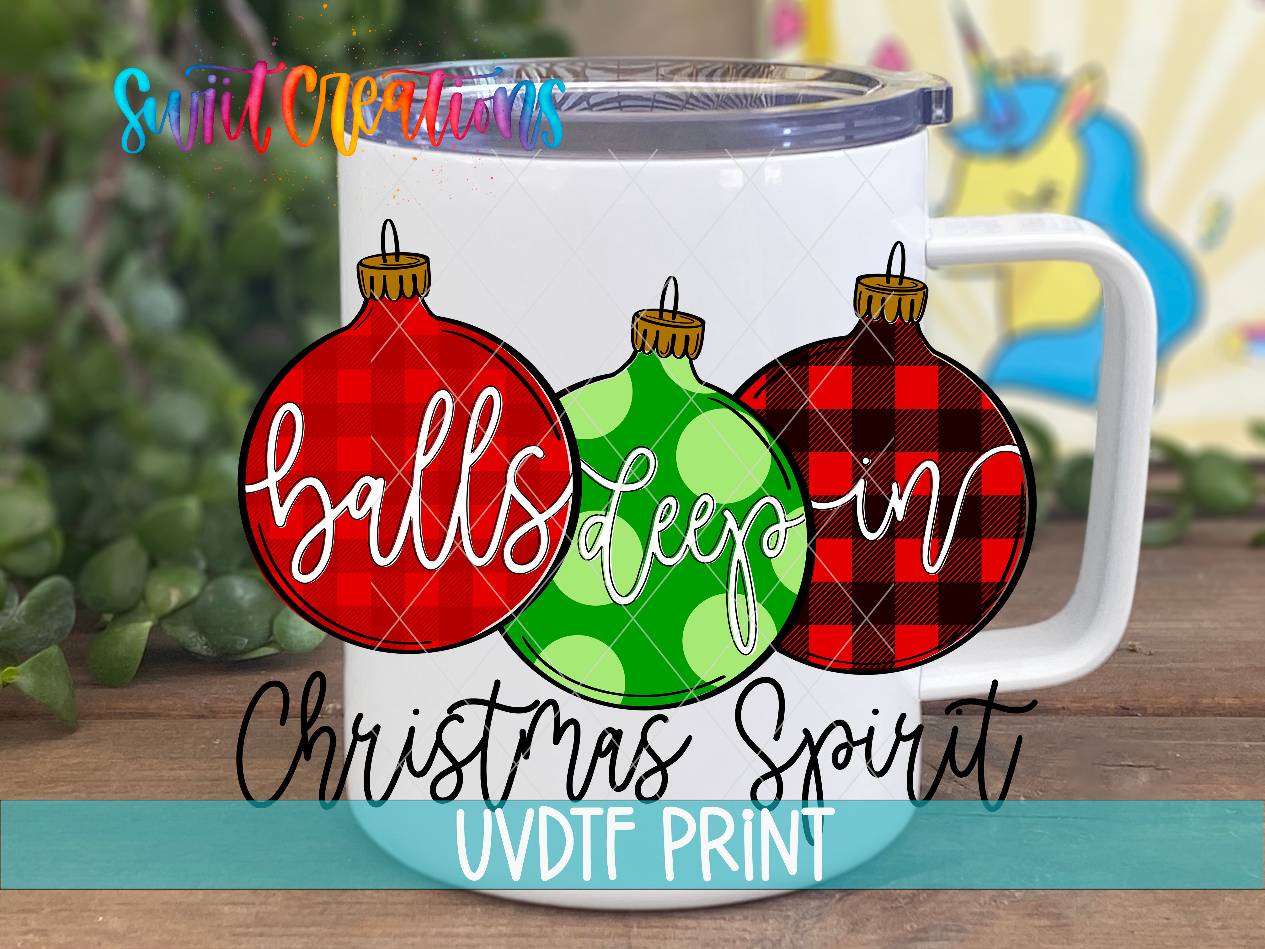 A white mug with a printed design featuring three Christmas ornaments in different colors and patterns.