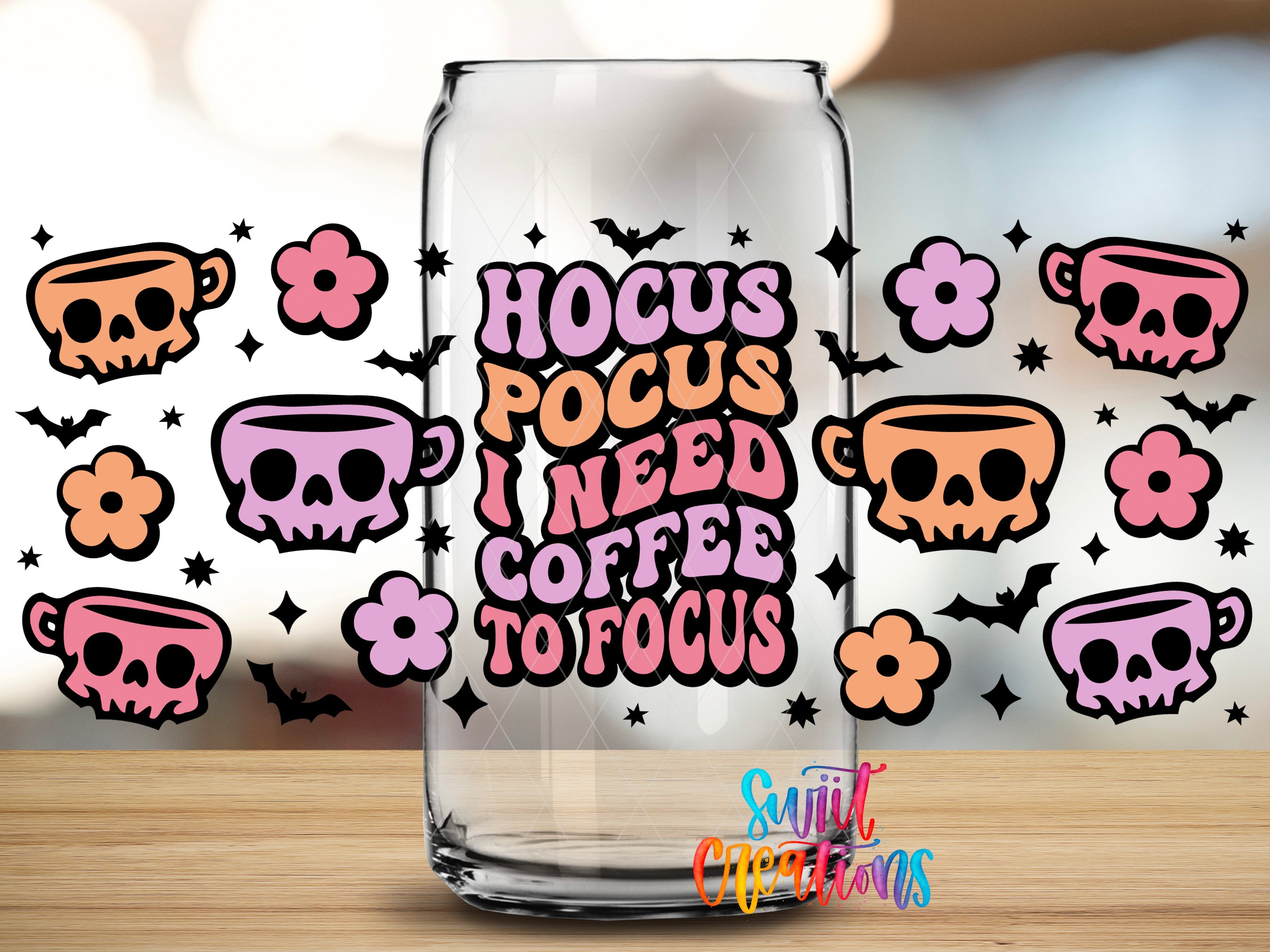 a glass can with a sticker that says "Hocus Pocus I need coffee to focus" surrounded by various skull and floral designs.