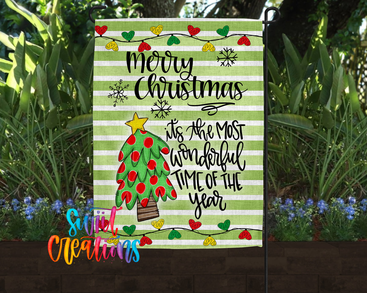A festive Christmas-themed garden flag with a green and white striped background, a red and white Christmas tree, and various holiday-themed decorations such as snowflakes and hearts.