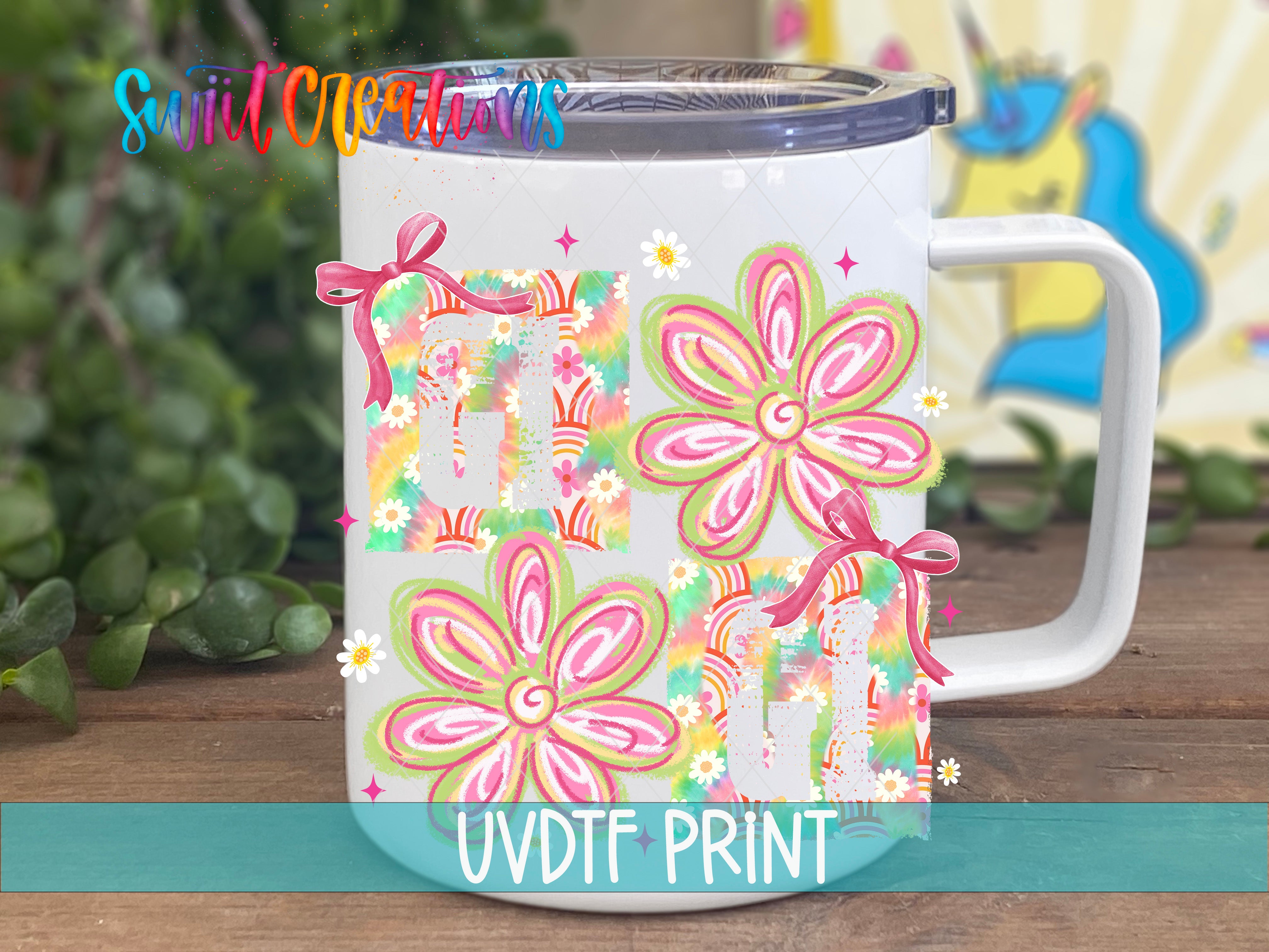 A white mug with a colorful floral design and bows on it, placed on a wooden surface.