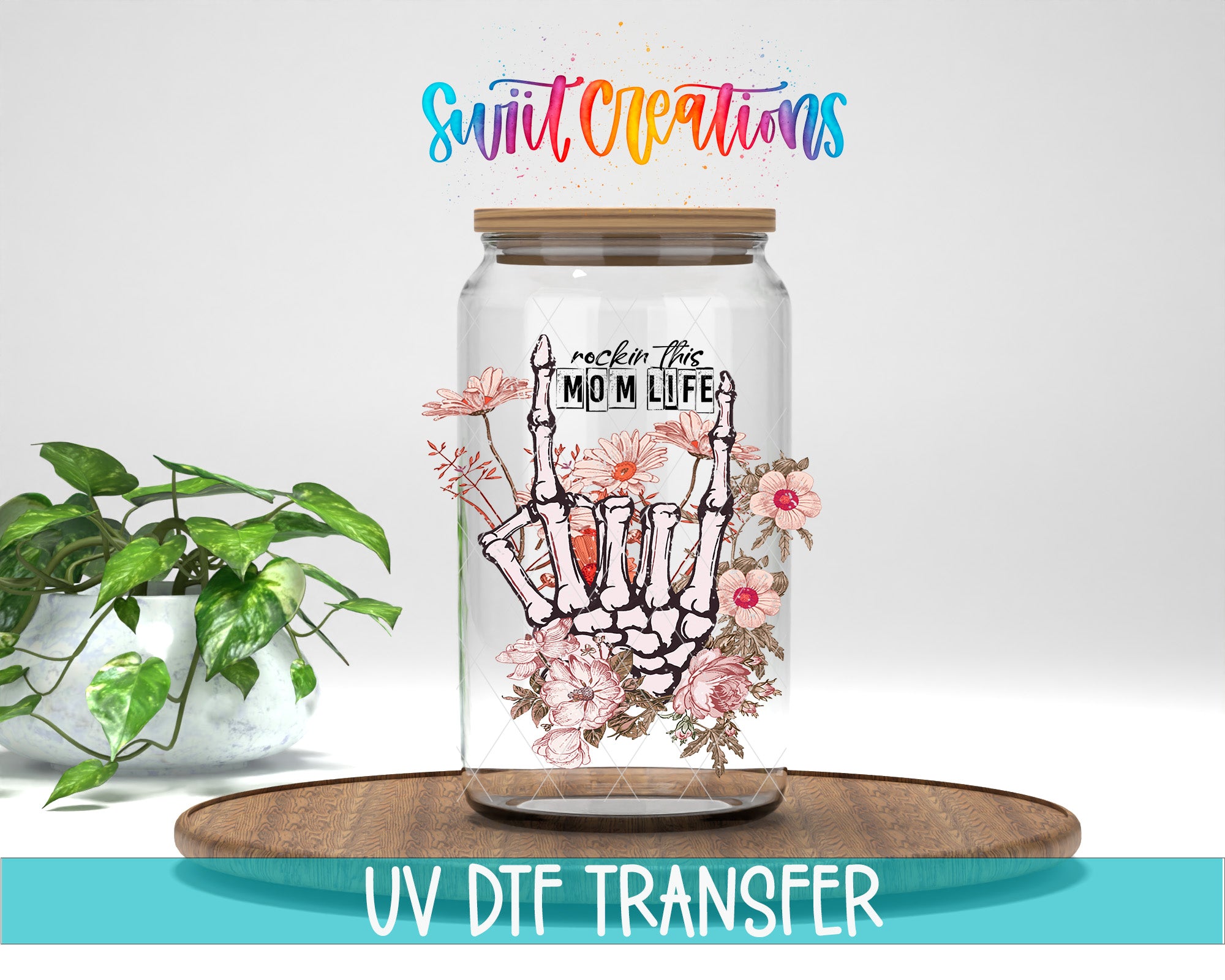 a glass jar with a skeleton hand and floral design, placed on a wooden surface. The jar is labeled "rock this mom life" and is accompanied by a UVDF Transfer watermark.
