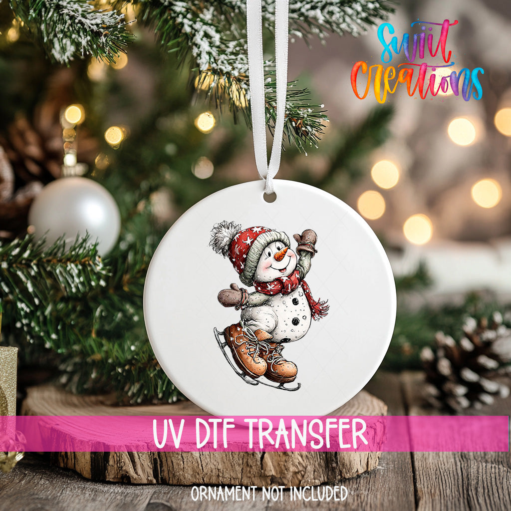 A white ornament with a snowman figure is hanging on a Christmas tree, with a blurred background of pine branches and twinkling lights.
