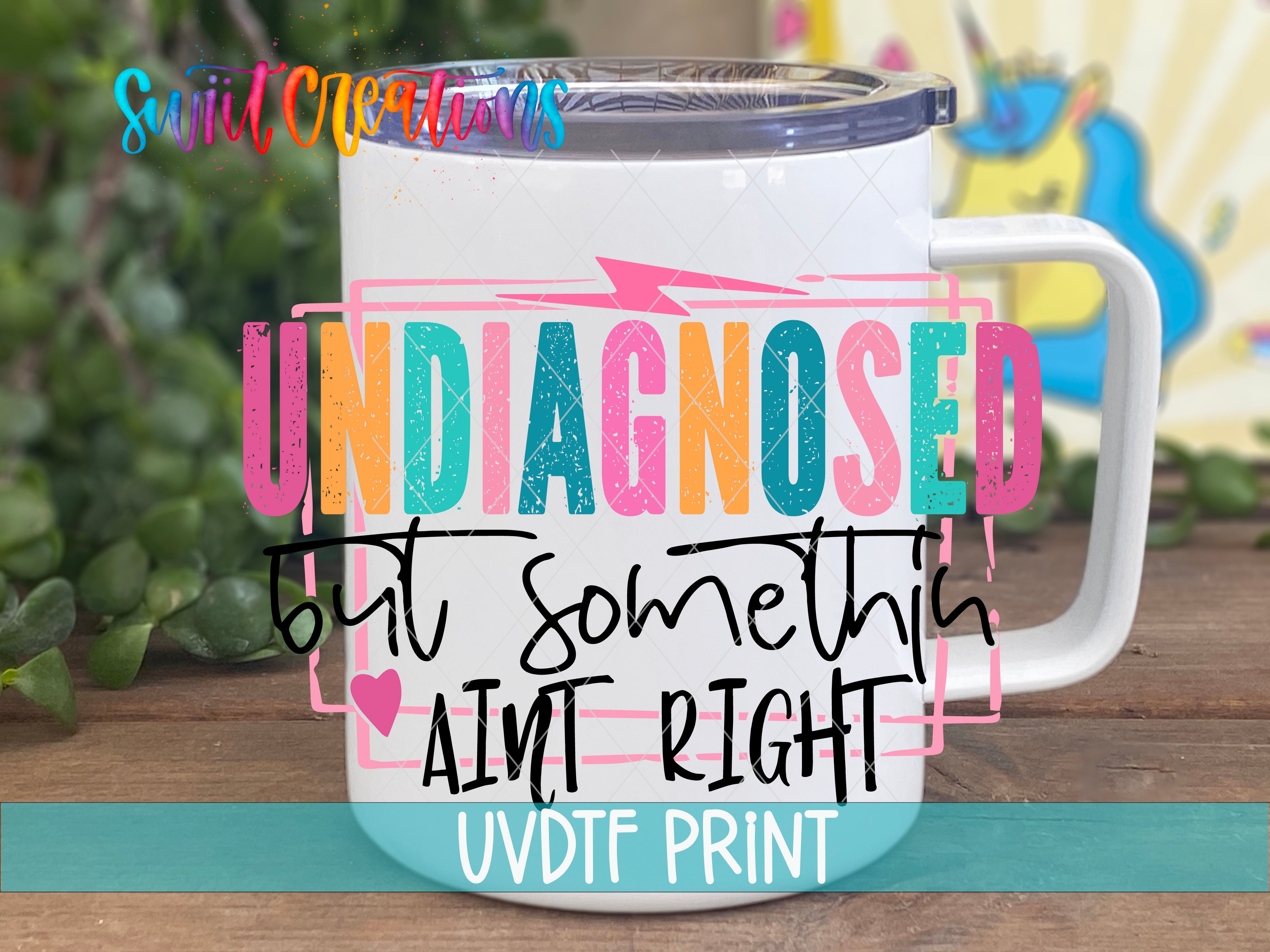 A white mug with colorful text and graphics on it, placed on a wooden surface.