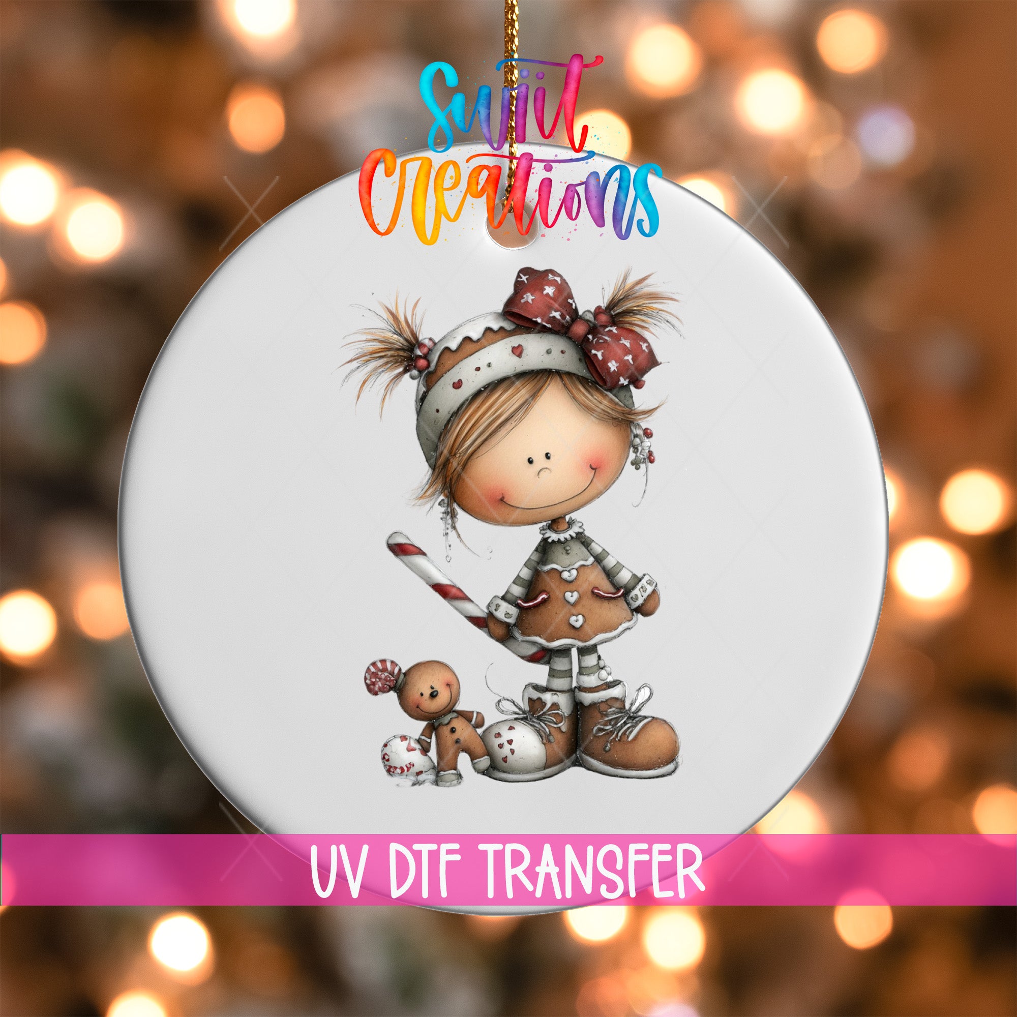A white ornament featuring a smiling girl with a bow on her head, holding a gingerbread man, and a small stuffed animal. The ornament is hanging against a background with colorful lights.
