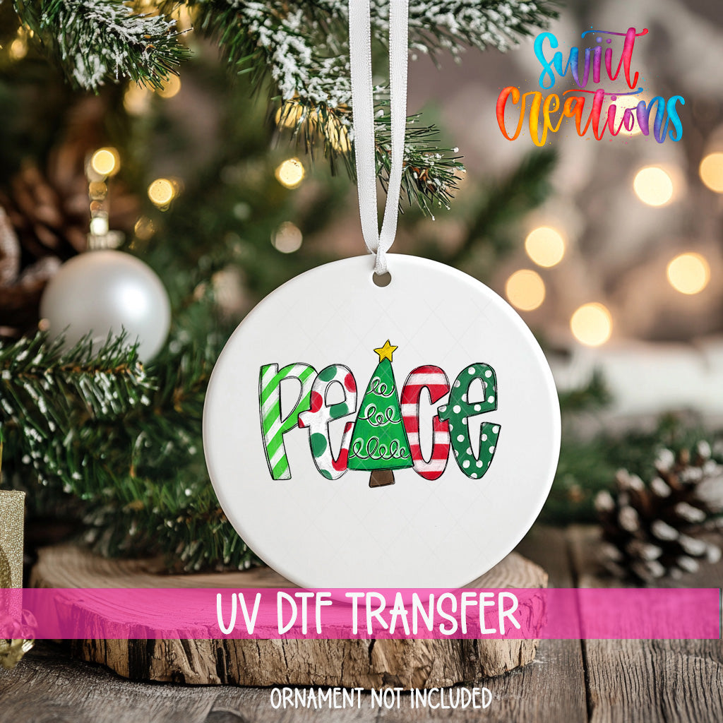A white ornament with the word "Peace" written on it, hanging on a Christmas tree.