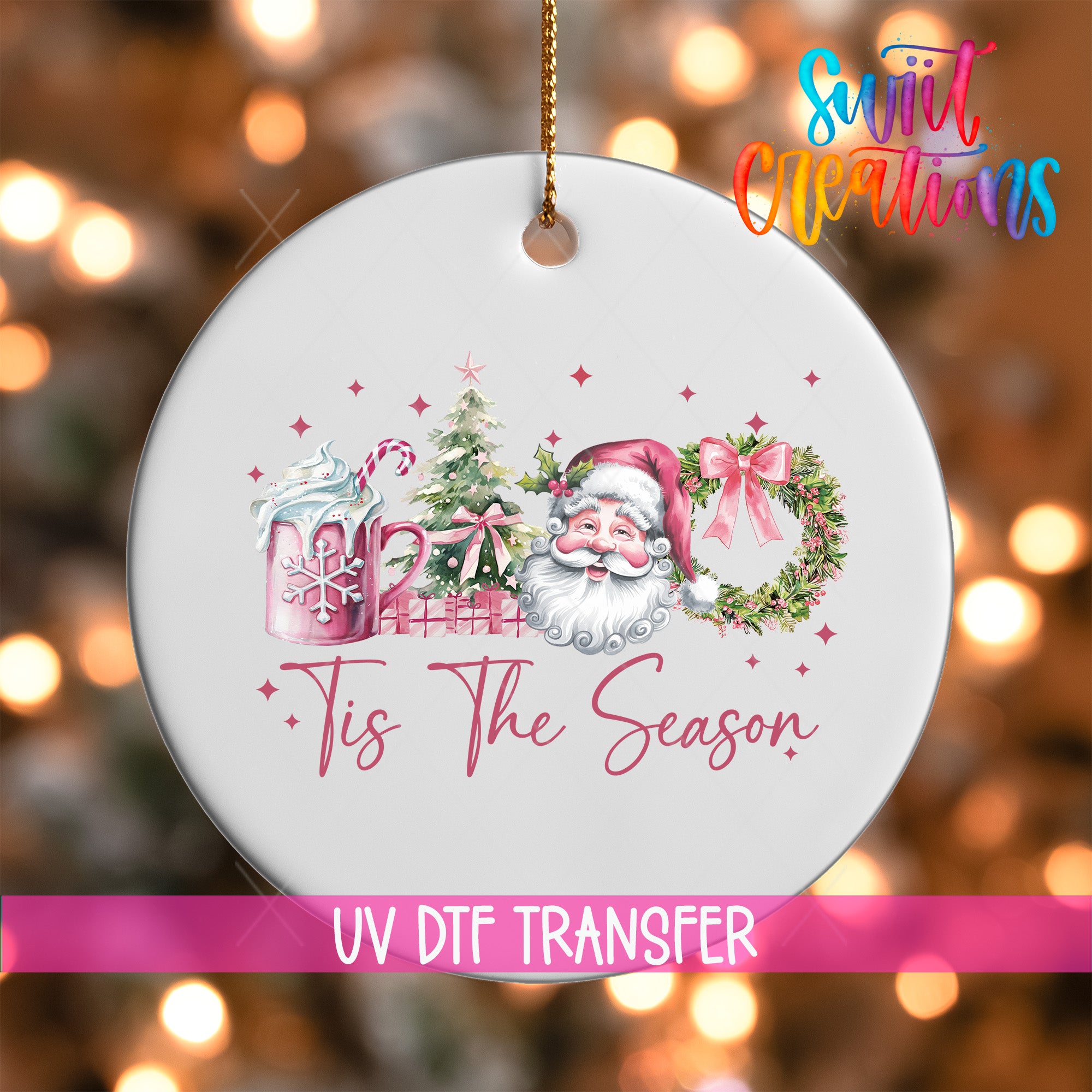 A white ornament with a Santa Claus design and the text "Tis The Season" hanging from a string.