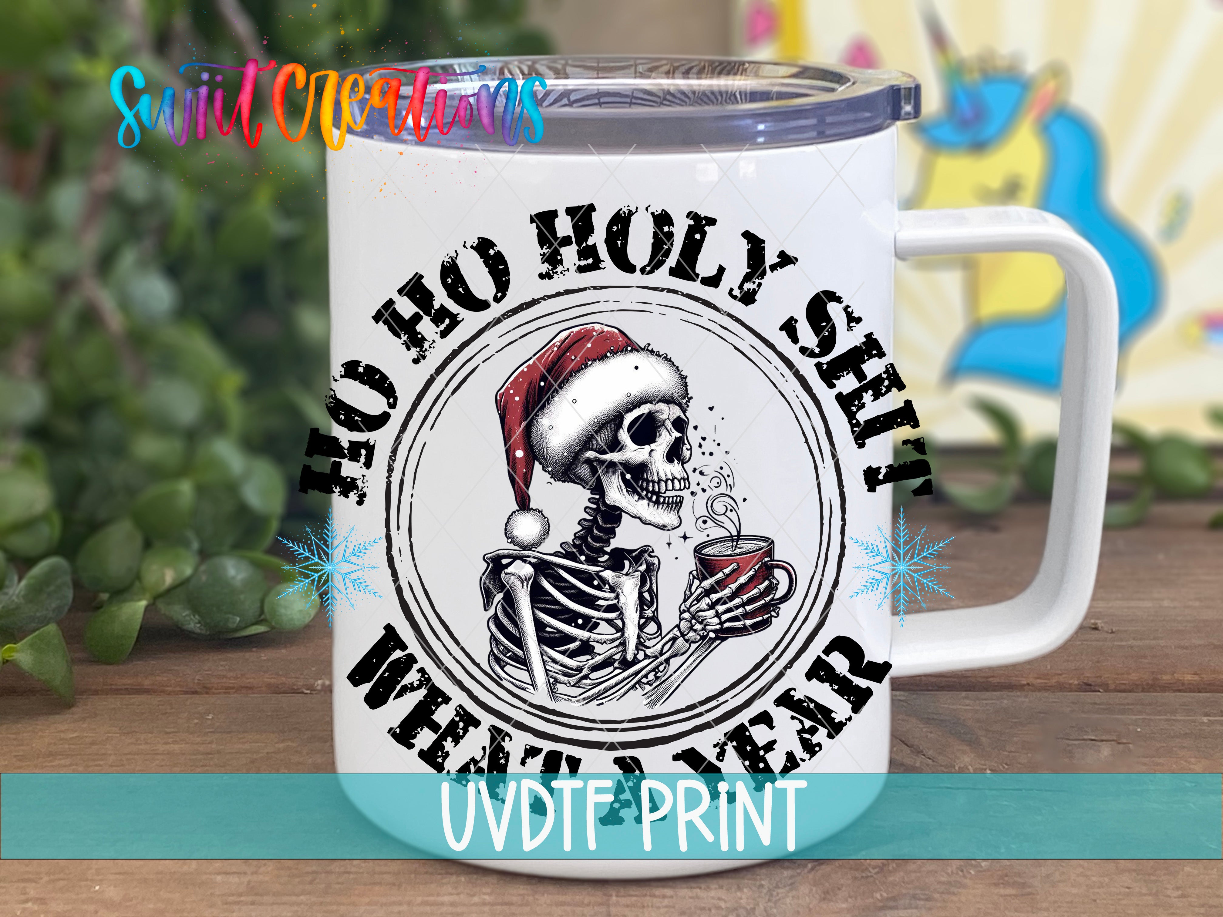 A white mug with a black and white illustration of a skeleton wearing a Santa hat and holding a cup of coffee. The mug has a text design that says "Hoo Ho Holy shit When I'm a year old".