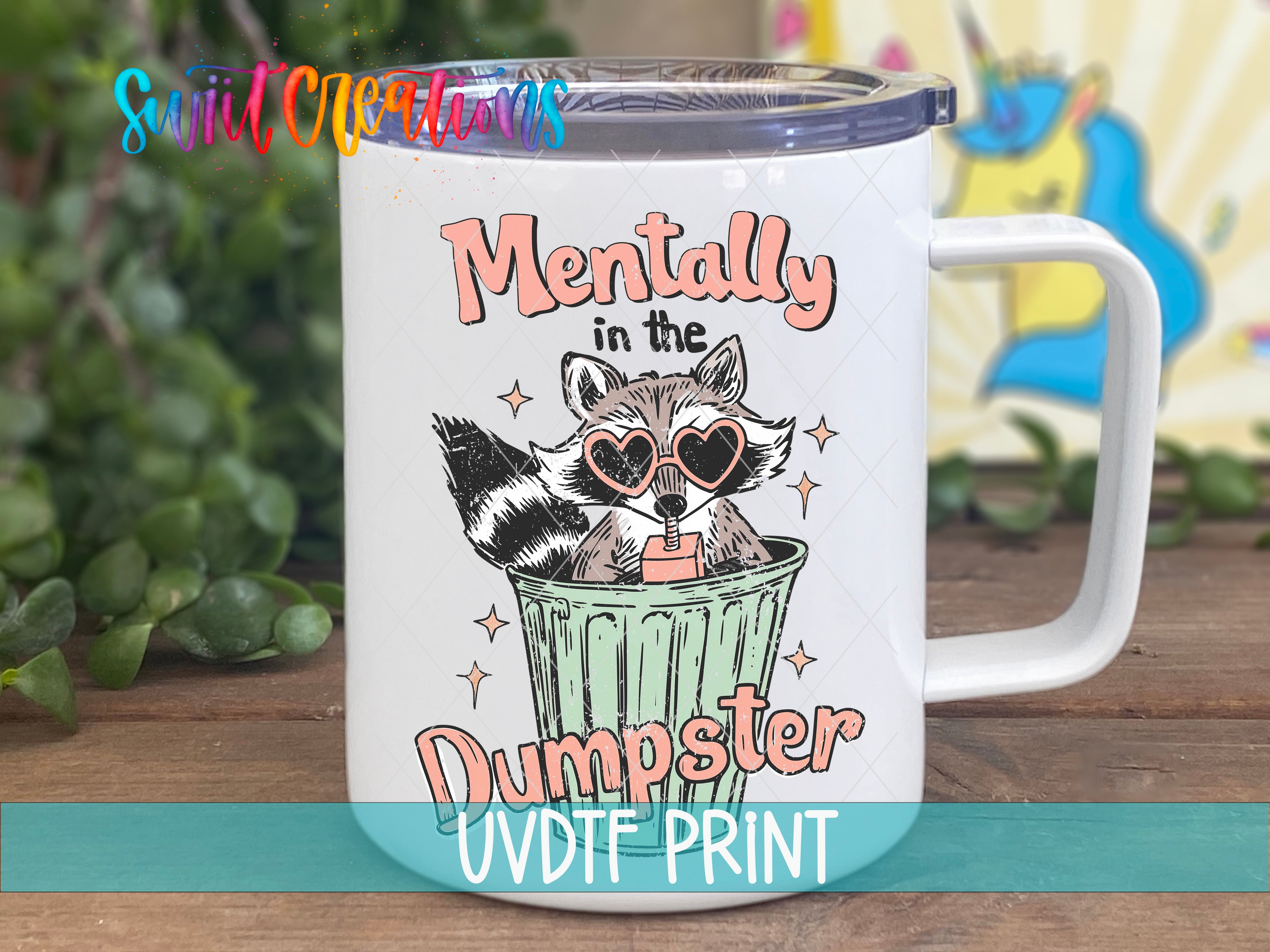 A white mug with a colorful design featuring a raccoon wearing sunglasses and the text "Mentally in the Dumpster" printed on it.
