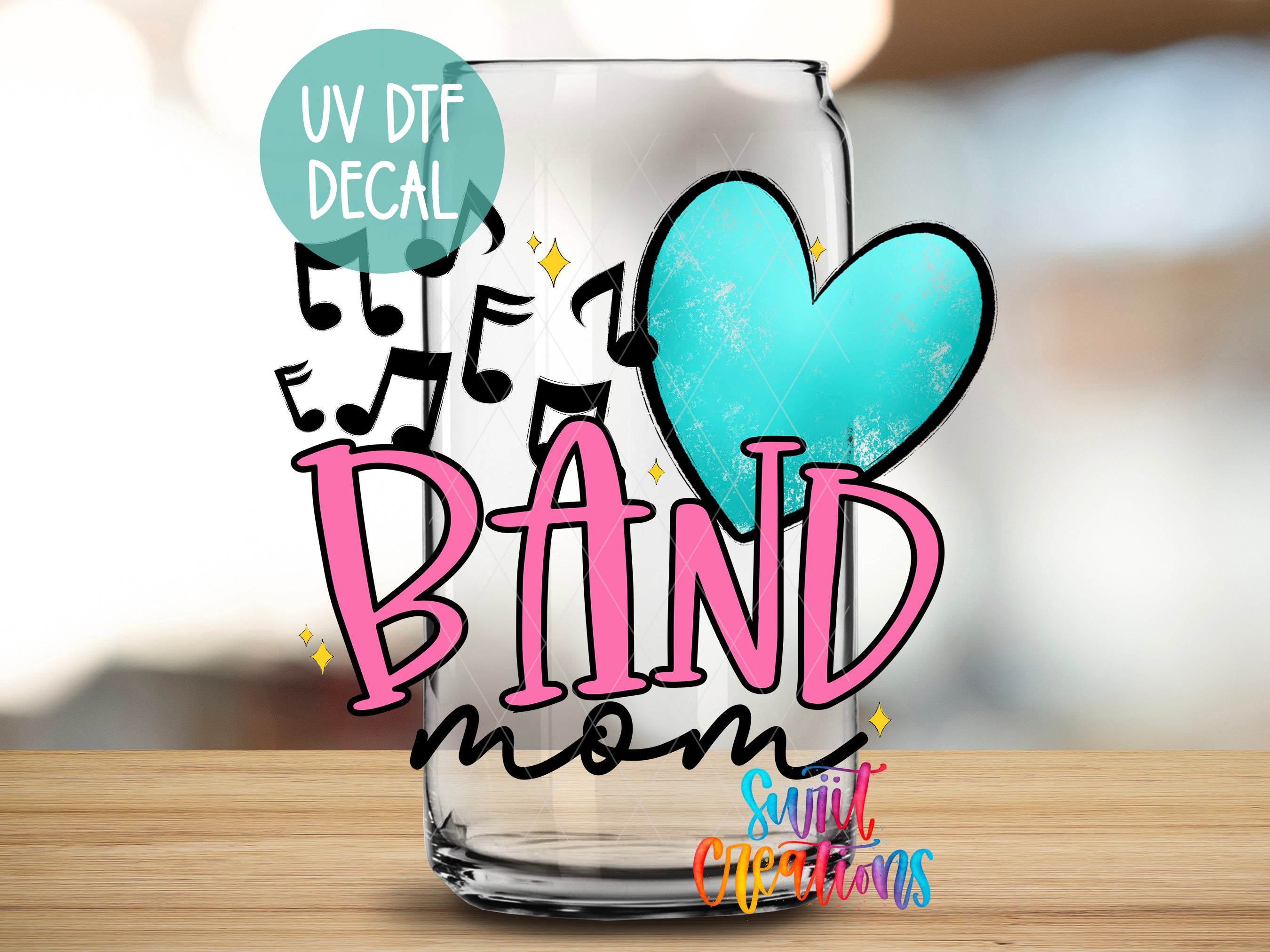 A glass with a heart-shaped sticker and the text "BAND mom" written on it, along with some musical notes and a UV decal.