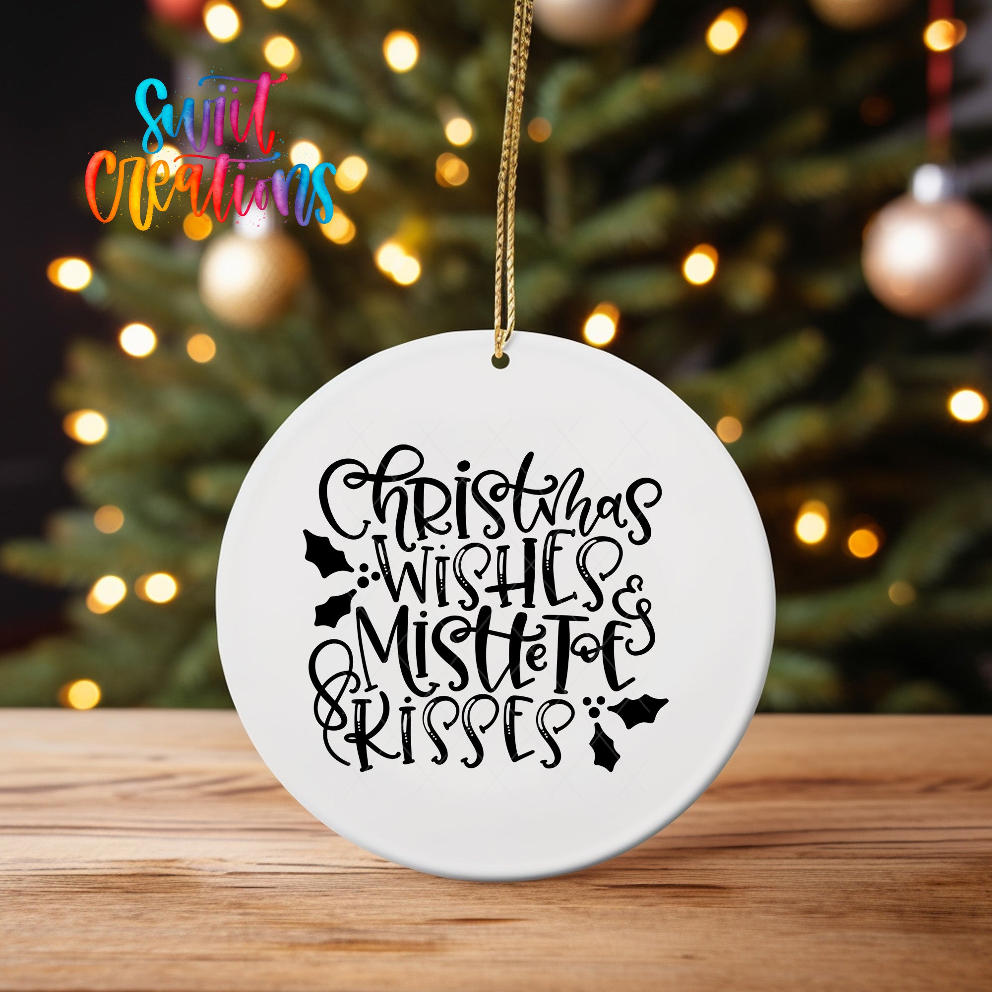 A white ceramic ornament with the text "Christmas Wishes & Mistletoe Kisses" written on it, hanging from a string.