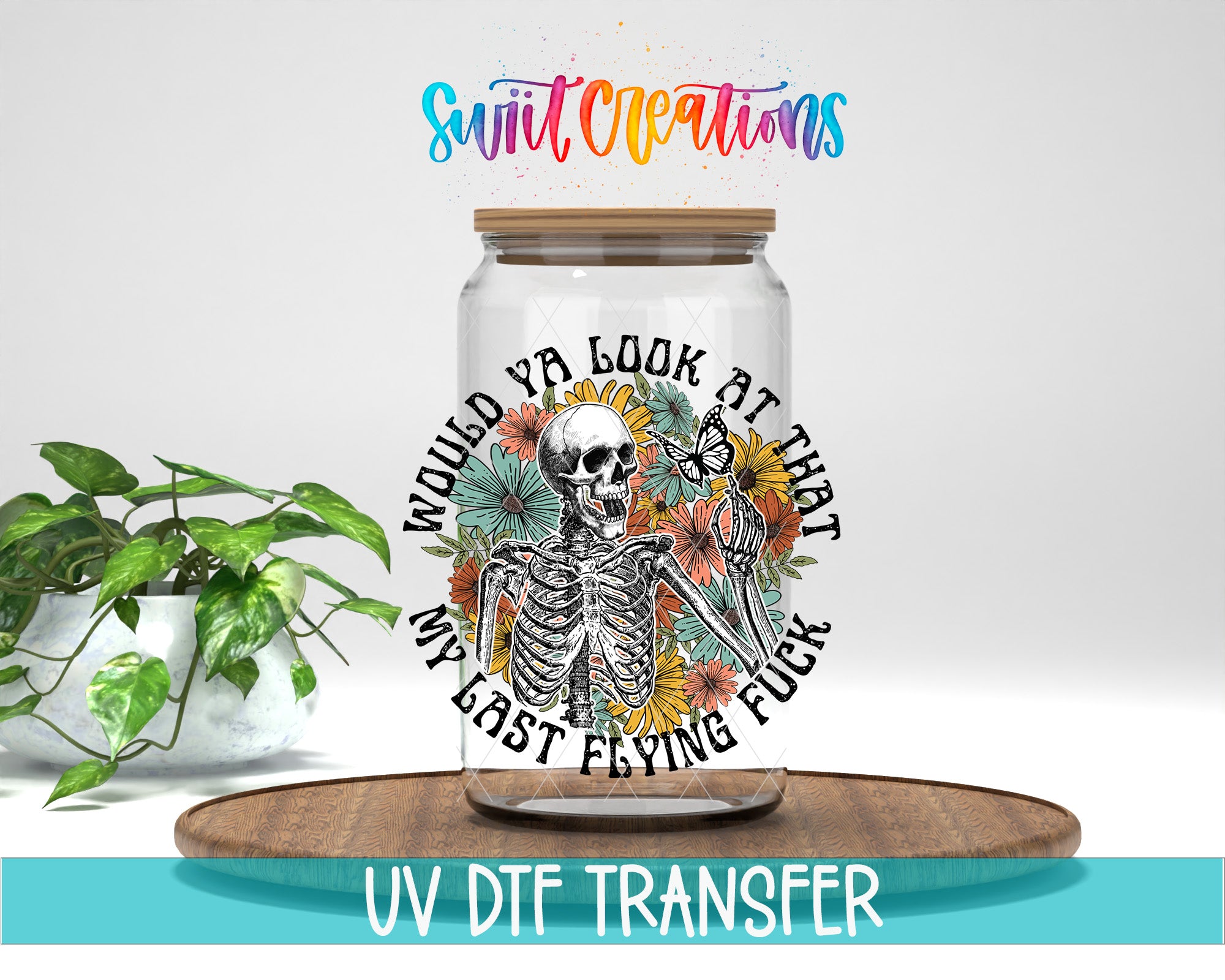 a glass jar with a skeleton and colorful flowers on it, placed on a wooden surface.