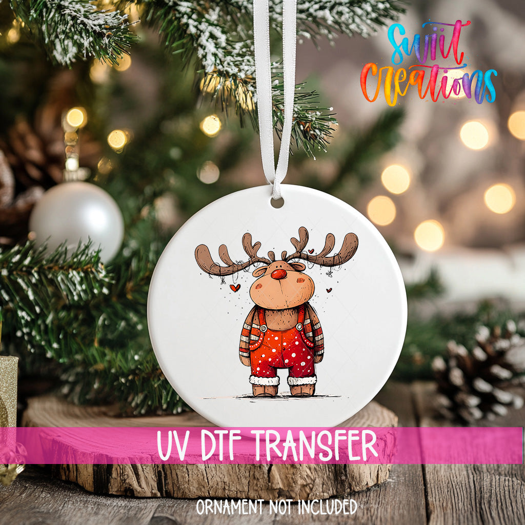 A white ornament with a cartoon reindeer on it, hanging on a Christmas tree.