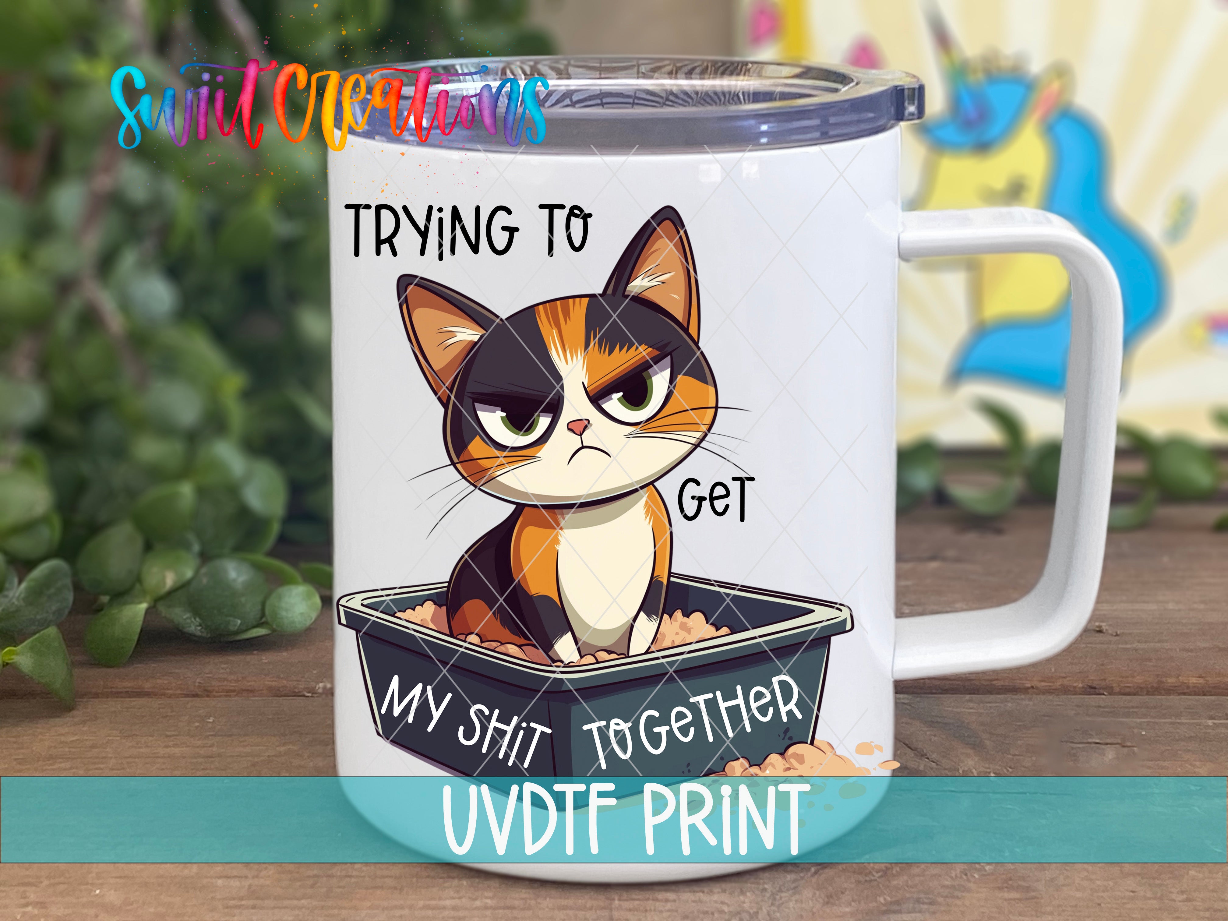 A mug with a cartoon cat sitting in a litter box and the text "Trying to get my shit together" printed on it.