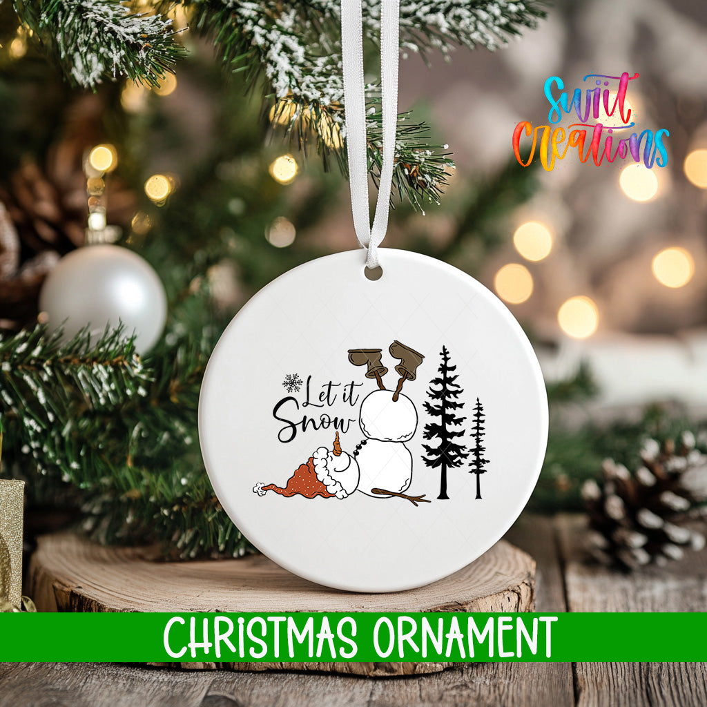 A white Christmas ornament with a snowman and the text "Let it Snow" is hanging on a tree.