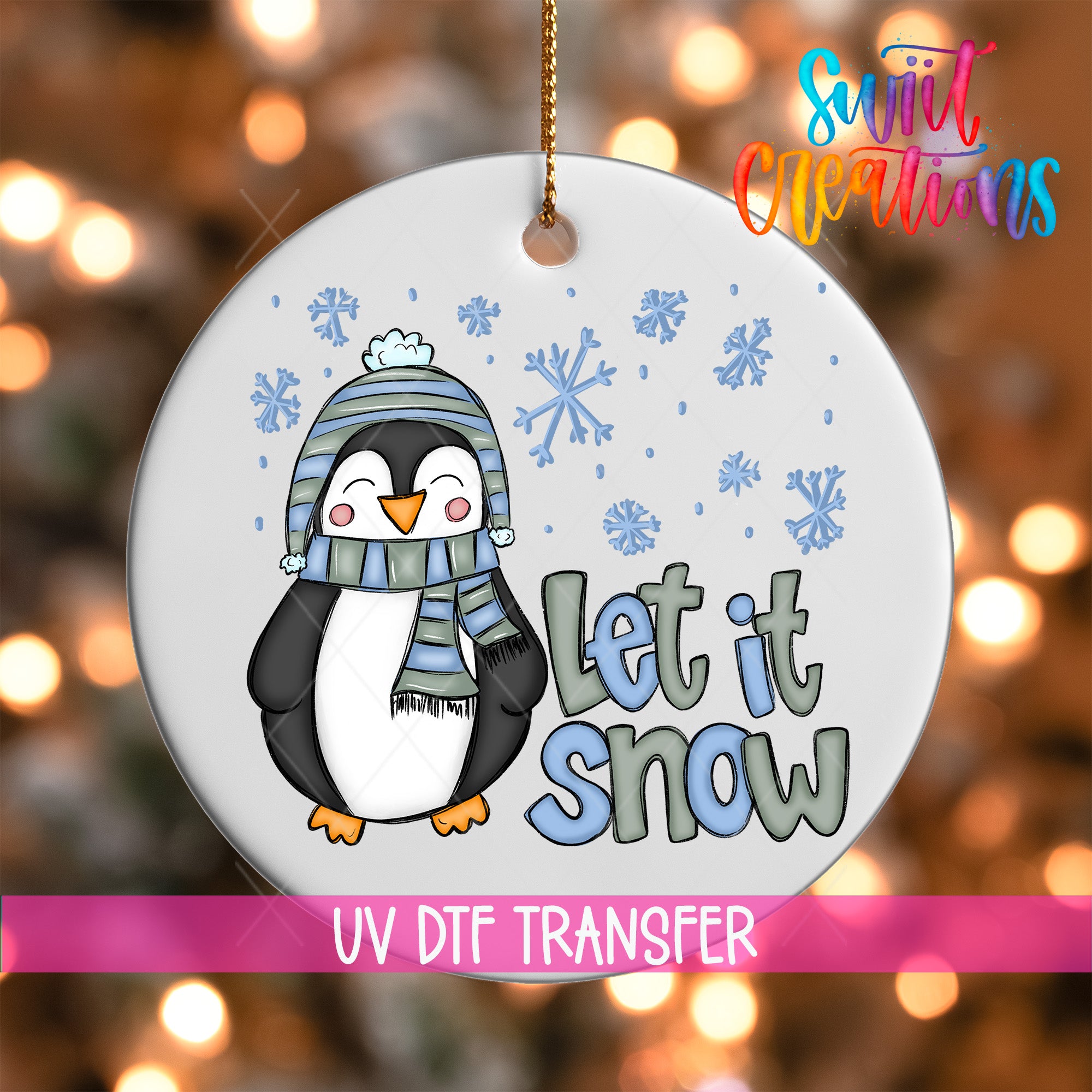 A white ornament with a cartoon penguin wearing a scarf and hat, surrounded by snowflakes, and the text "Let it snow" written below.