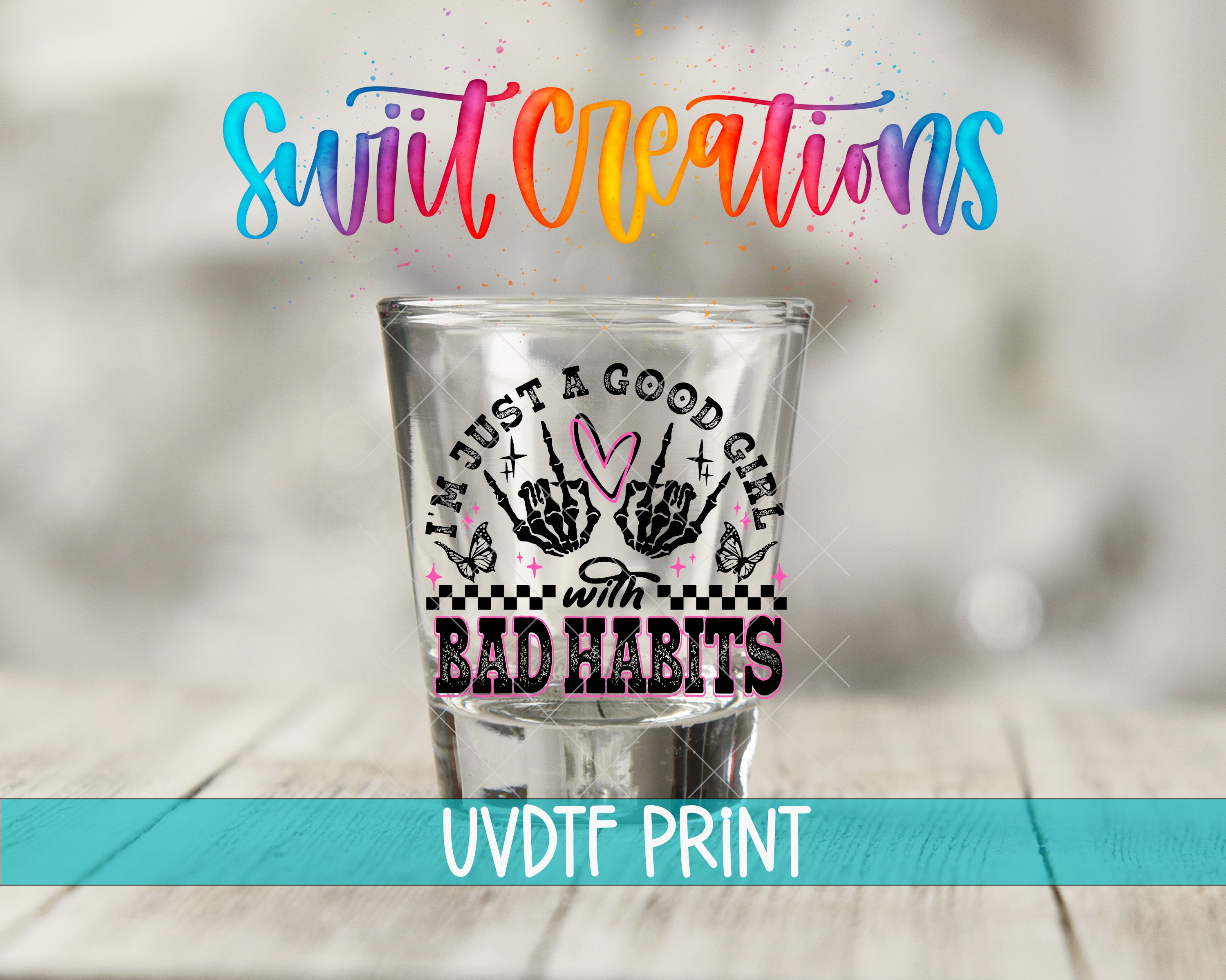a shot glass with a colorful, hand-drawn design and text on it, placed on a wooden surface.