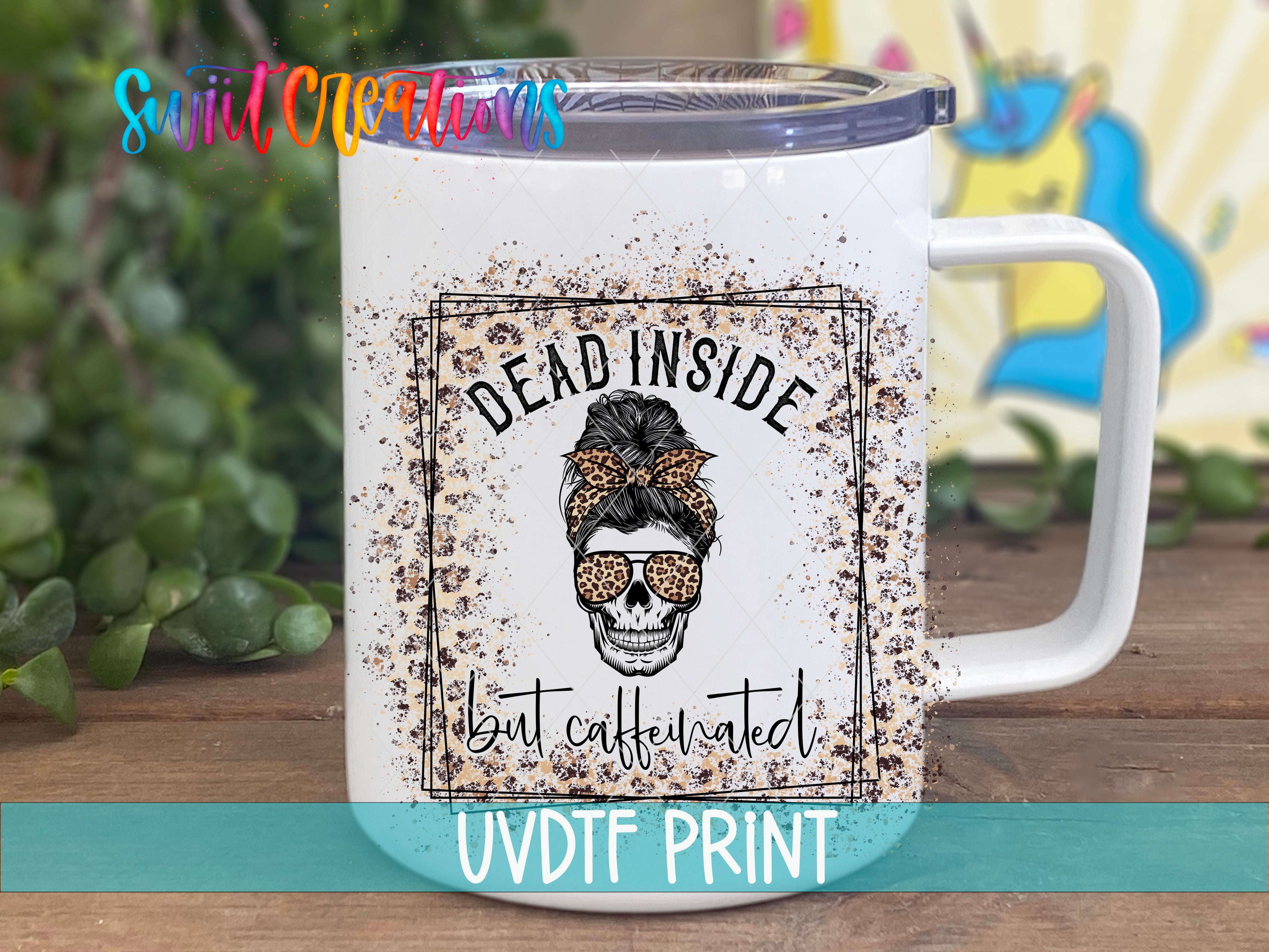 A white mug with a black and white skull design and the text "Dead inside but caffeinated" printed on it.