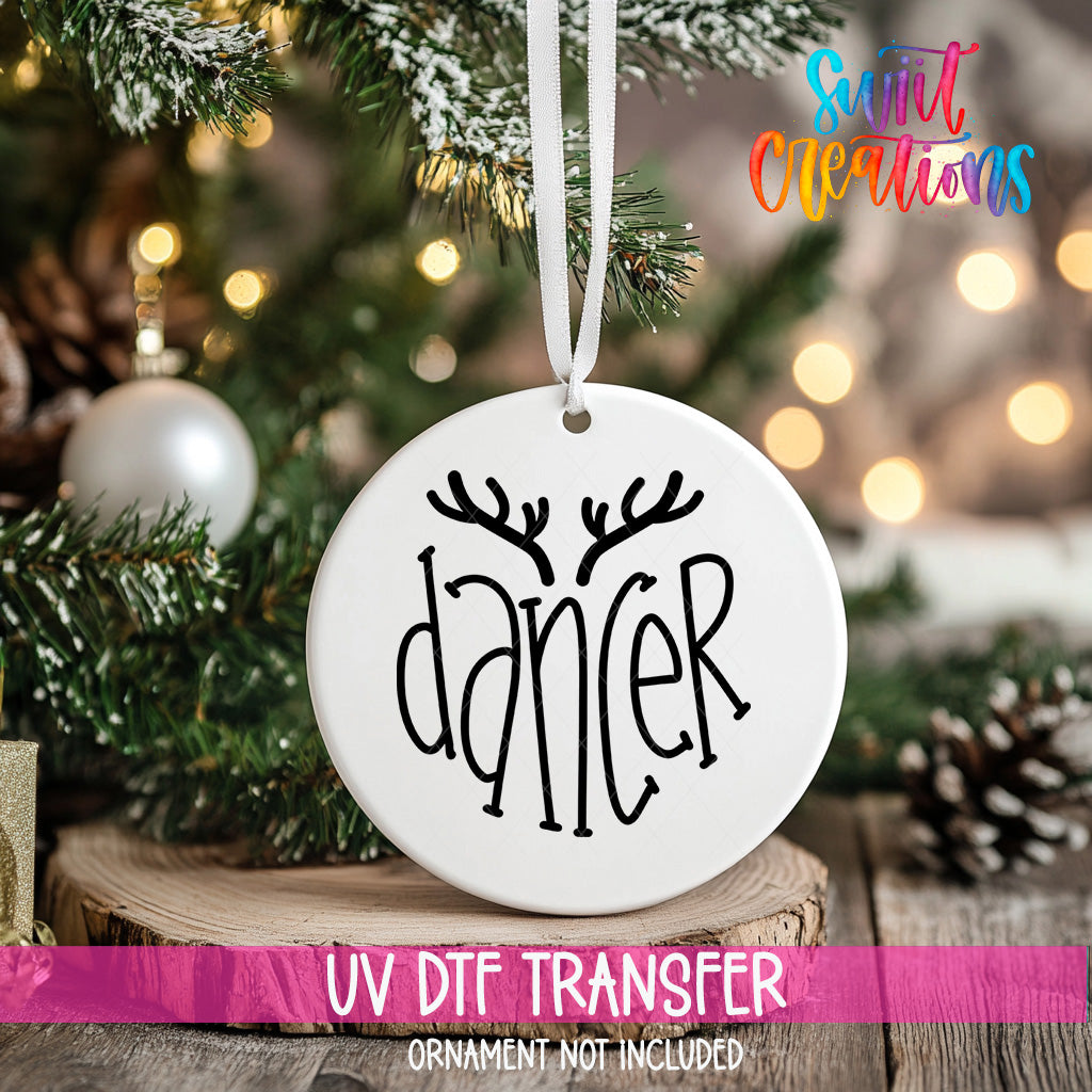 A white ornament with the word "dancer" written on it, hanging on a Christmas tree.