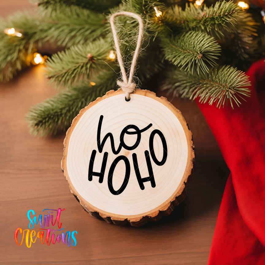 A wooden ornament with the text "ho ho" hanging from a tree branch, surrounded by pine branches and twinkling lights.