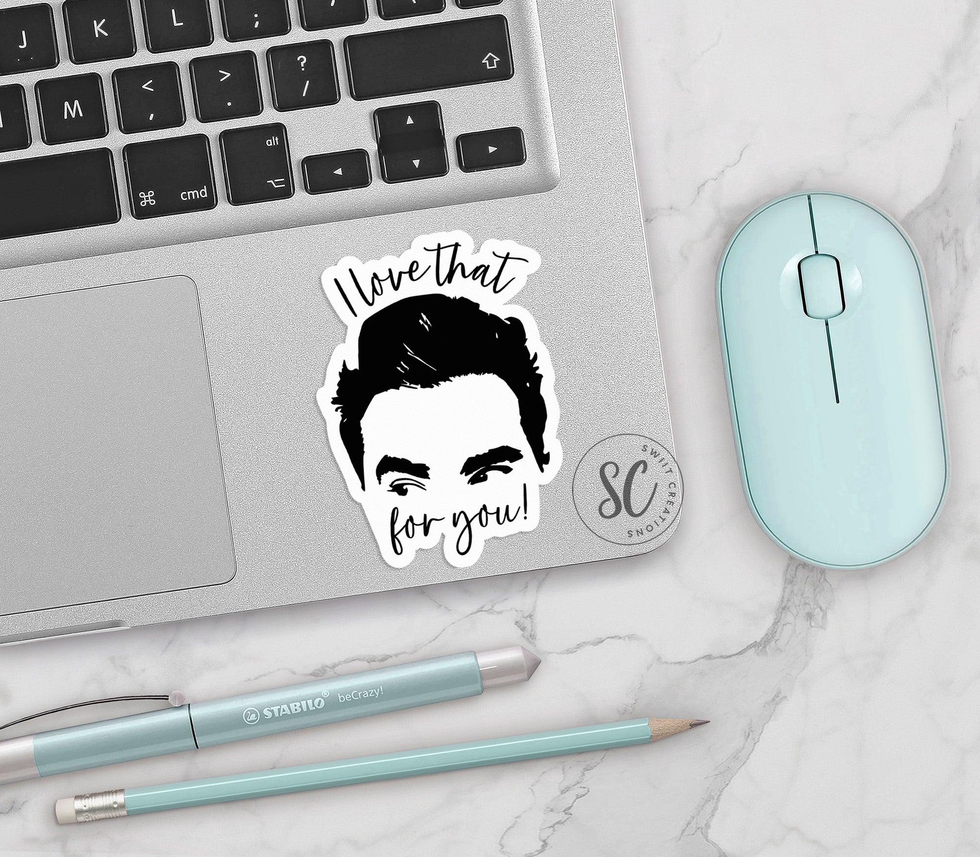 a laptop with a sticker of a man's face next to a mouse