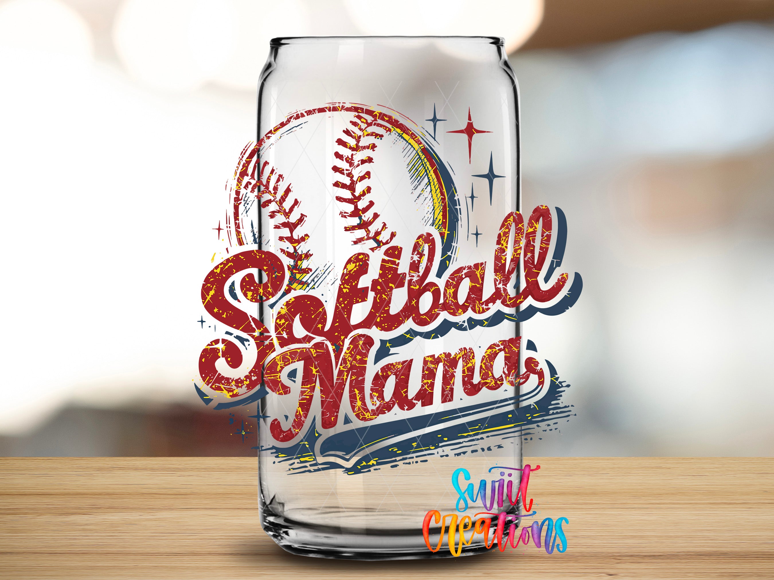 A glass can with a design featuring a baseball and the text "Softball Mama" on it, placed on a wooden surface.