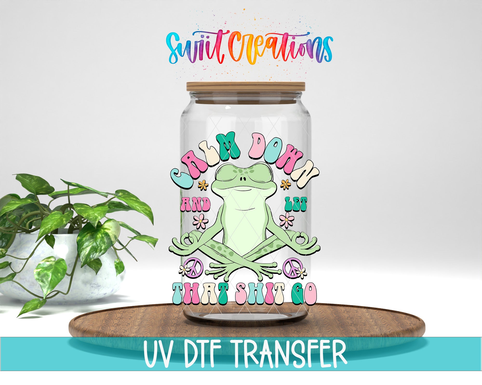 a glass jar with a frog illustration on it, placed on a wooden surface. The jar has a lid and is surrounded by a potted plant. The text above the jar reads "Swift Creations" and "CALM DOWN AND LET'S SHIT GO". The image is described as a "UV DFT Transfer" and is described as a "collage of multiple images".