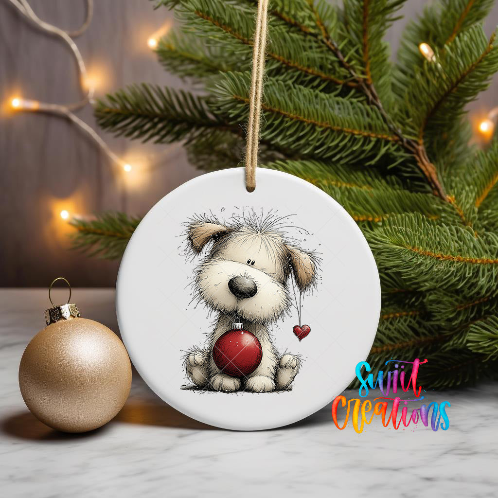 A ceramic ornament featuring a cartoon dog holding a red heart, placed on a marble surface next to a gold ornament and a Christmas tree with twinkling lights.