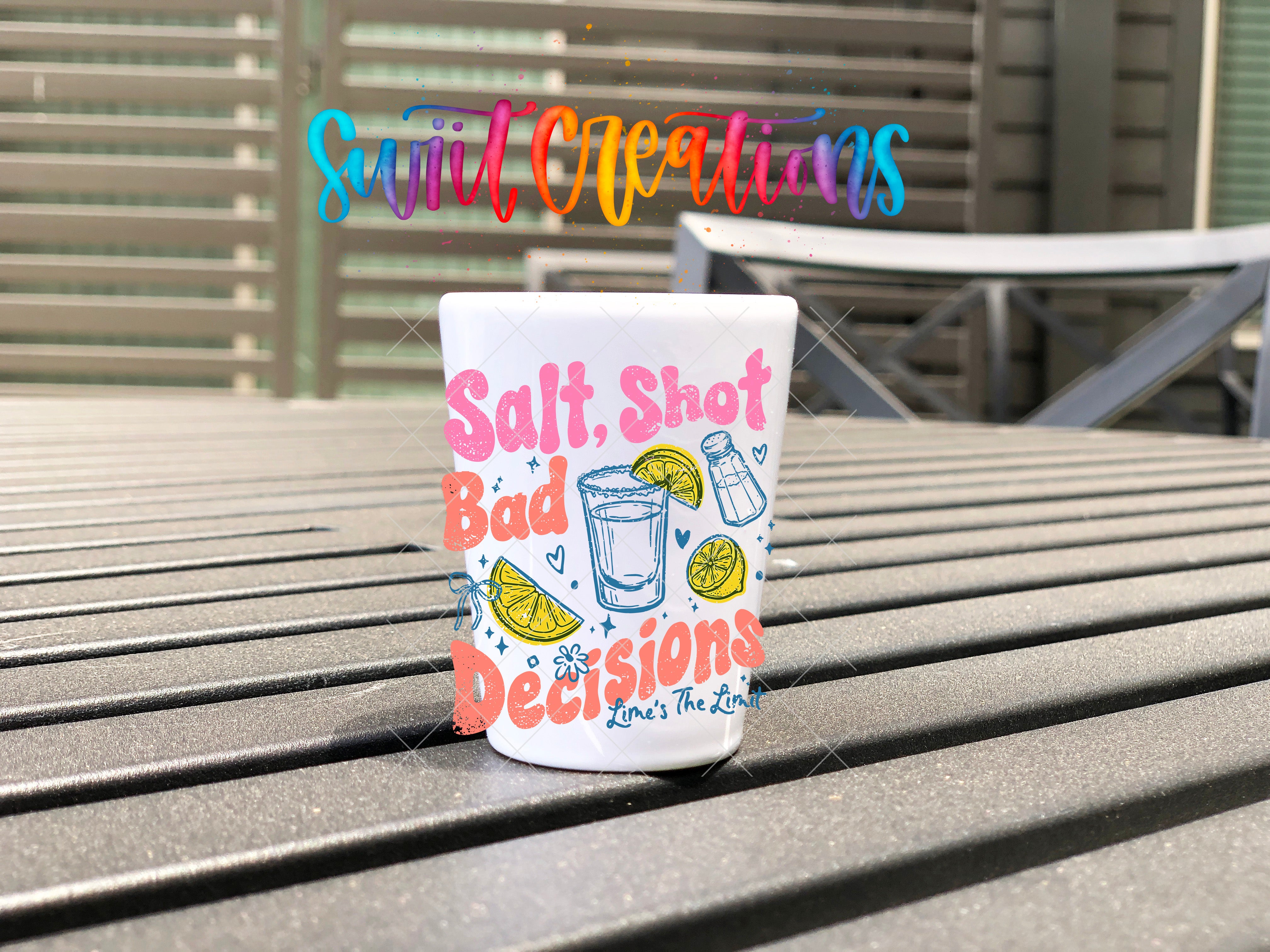 A colorful shot glass with the text "Salt, Shot, Bad Decisions" printed on it, placed on a wooden surface.