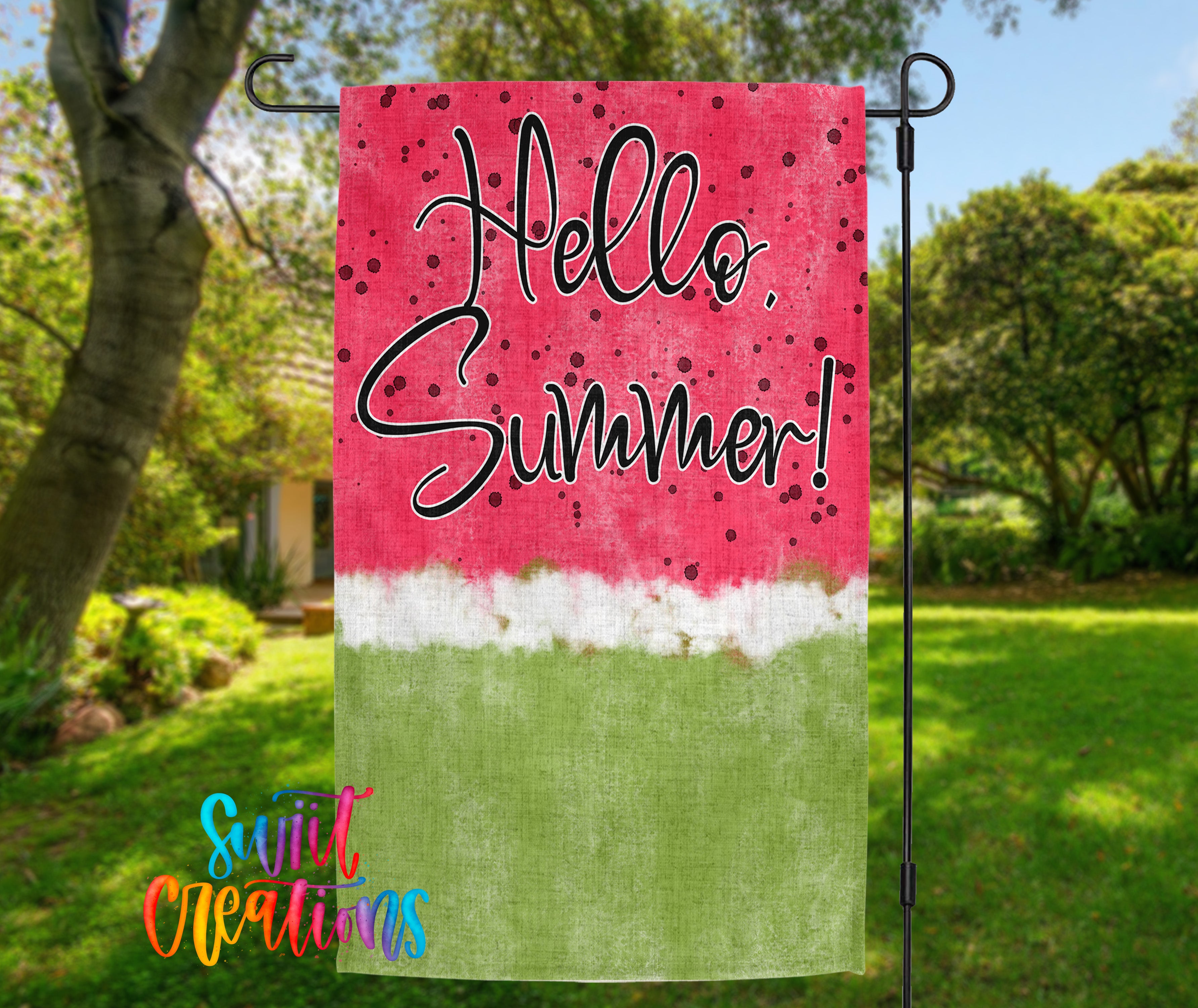 A colorful flag with the text "Hello Summer!" displayed on it, hanging in a grassy outdoor area with trees and a house in the background.