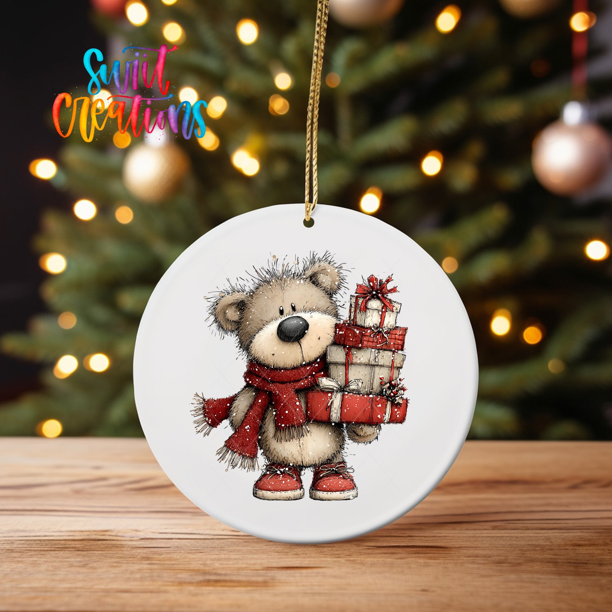 A white ornament featuring a teddy bear holding a stack of wrapped presents, with a Christmas tree in the background.
