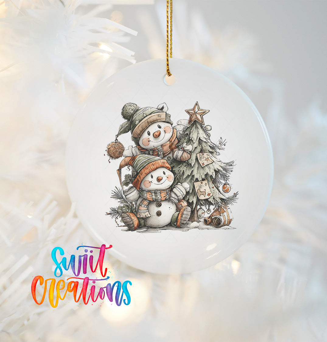 A white ornament with a snowman and a tree, along with a star decoration, hangs on a Christmas tree.