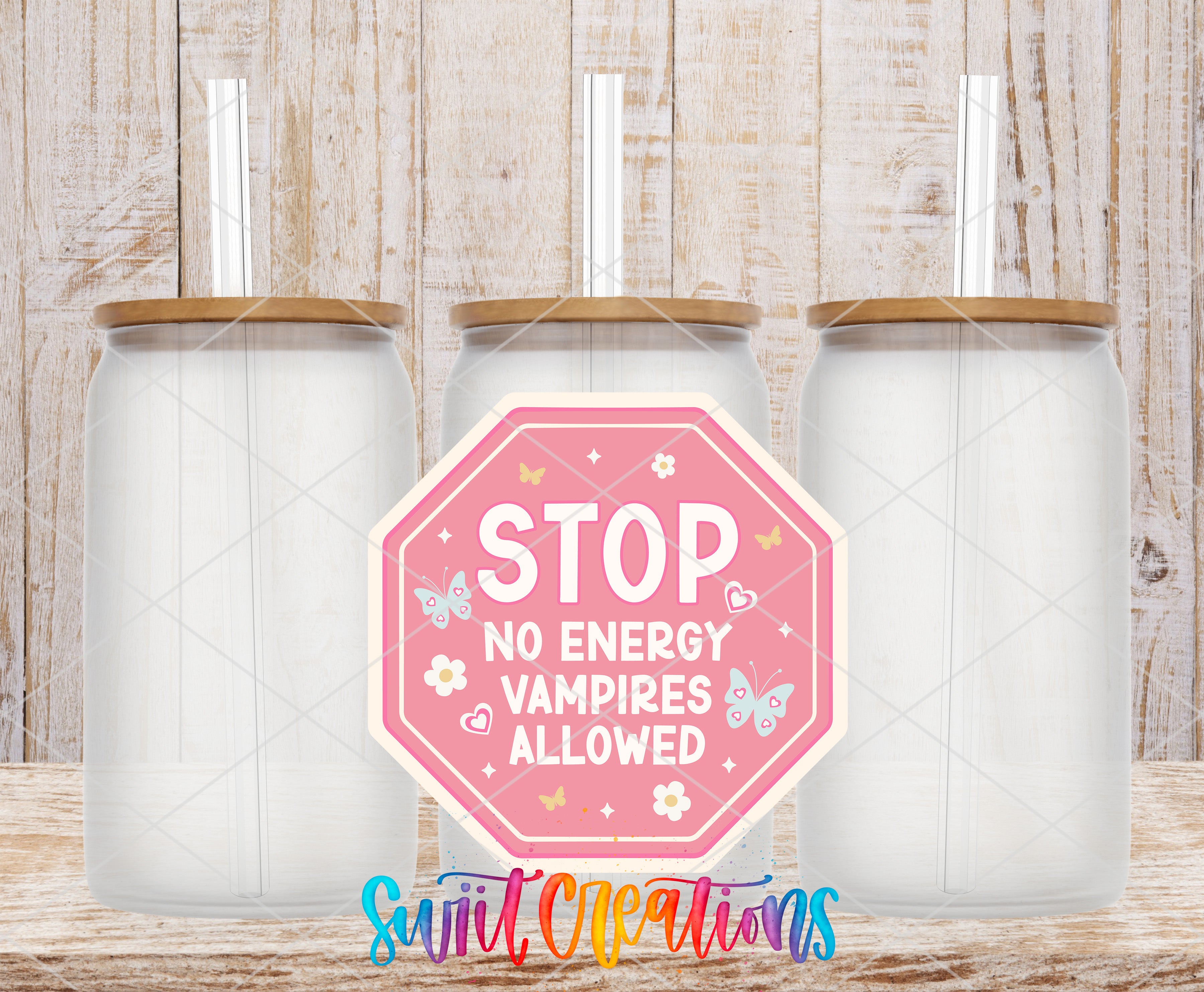 three transparent glass jars with wooden lids, arranged in a row against a wooden background. In front of the jars, there is a pink octagonal sign with the text "STOP NO ENERGY VAMPIRE ALLOWED" and various decorative elements such as butterflies and flowers.