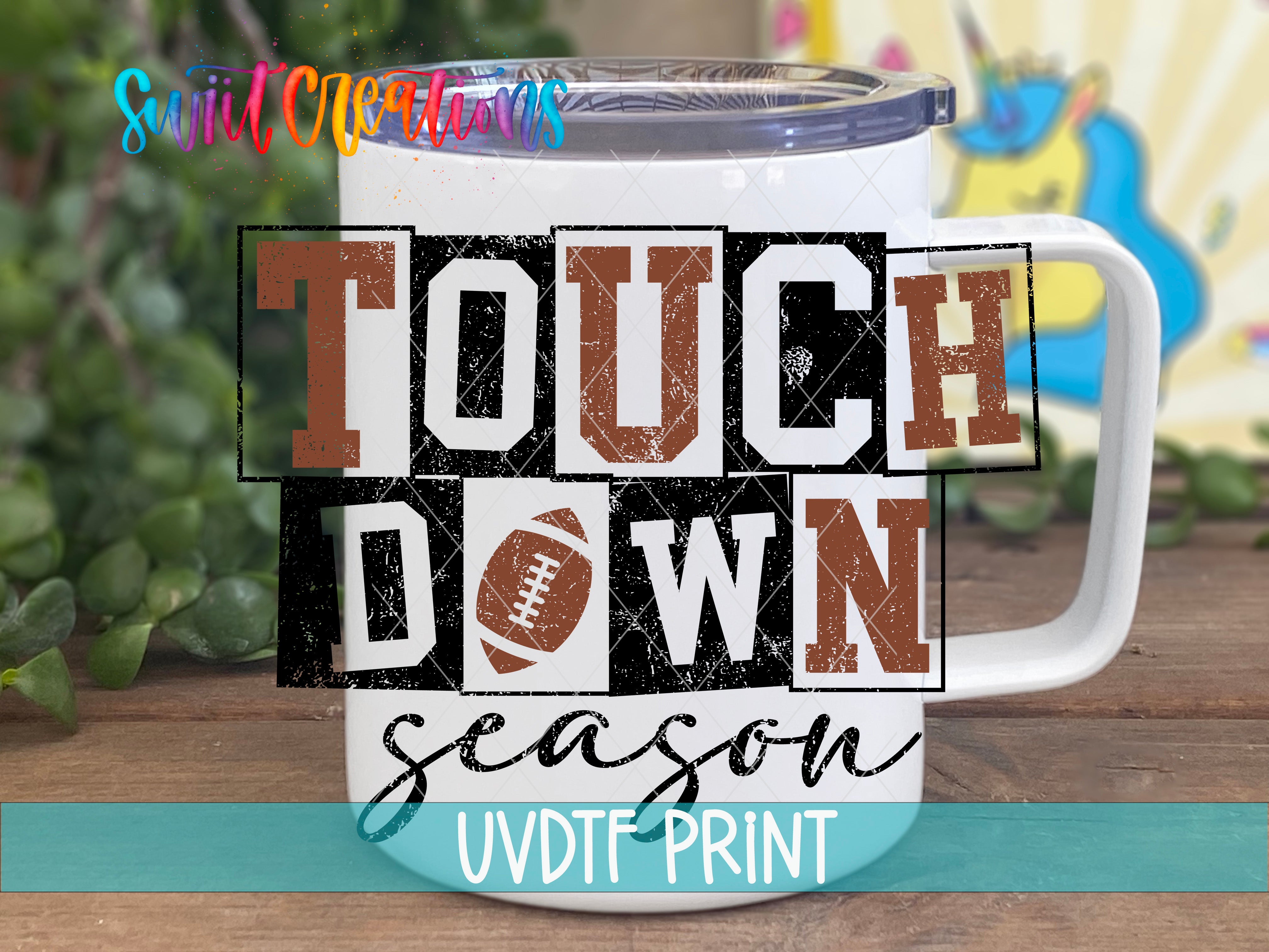 A white mug with the text "TOUCH DOWN" printed on it, along with the text "season UVDTFRINT" below it.