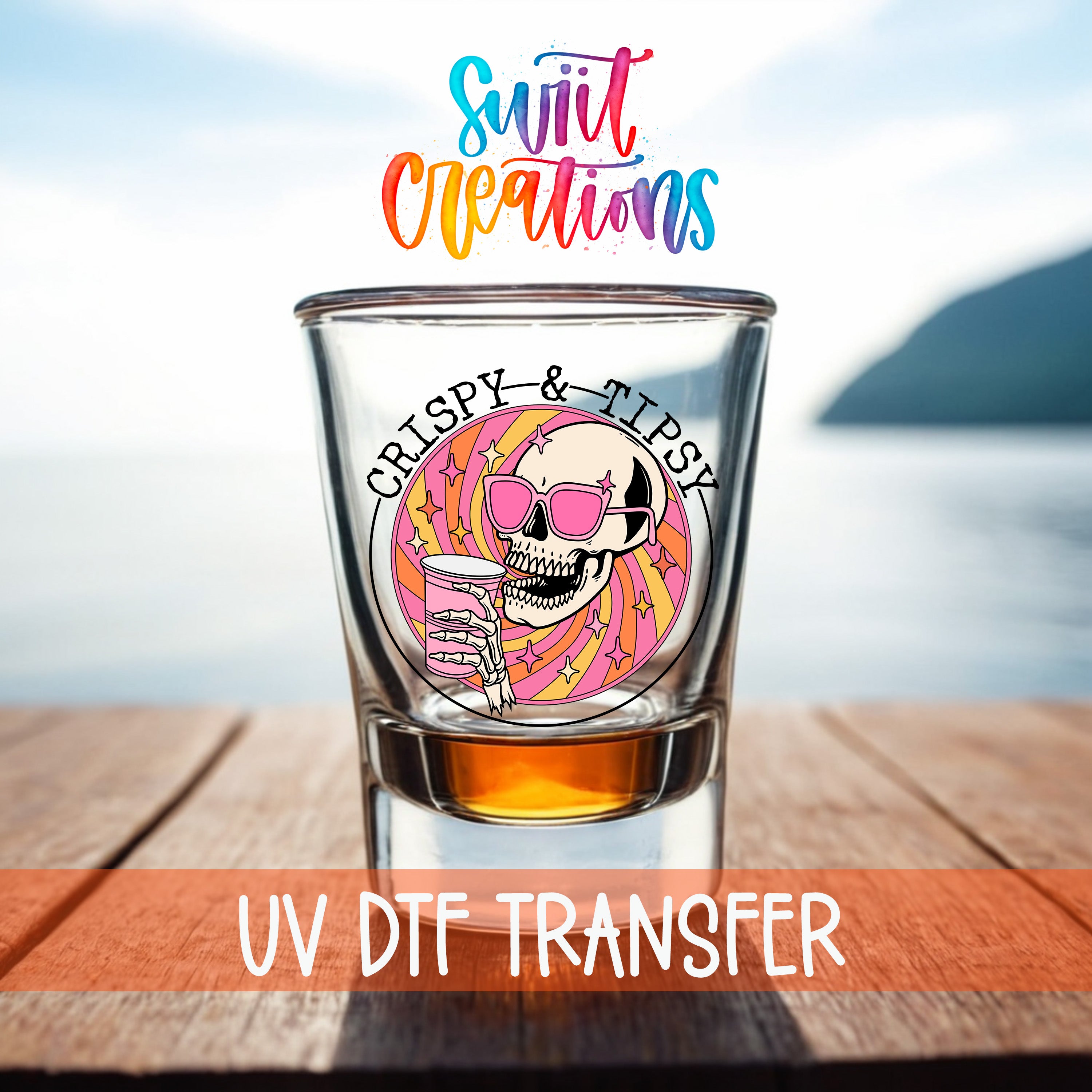 A shot glass with a skull wearing sunglasses and holding a drink, set against a blurred background of a body of water and a mountain.