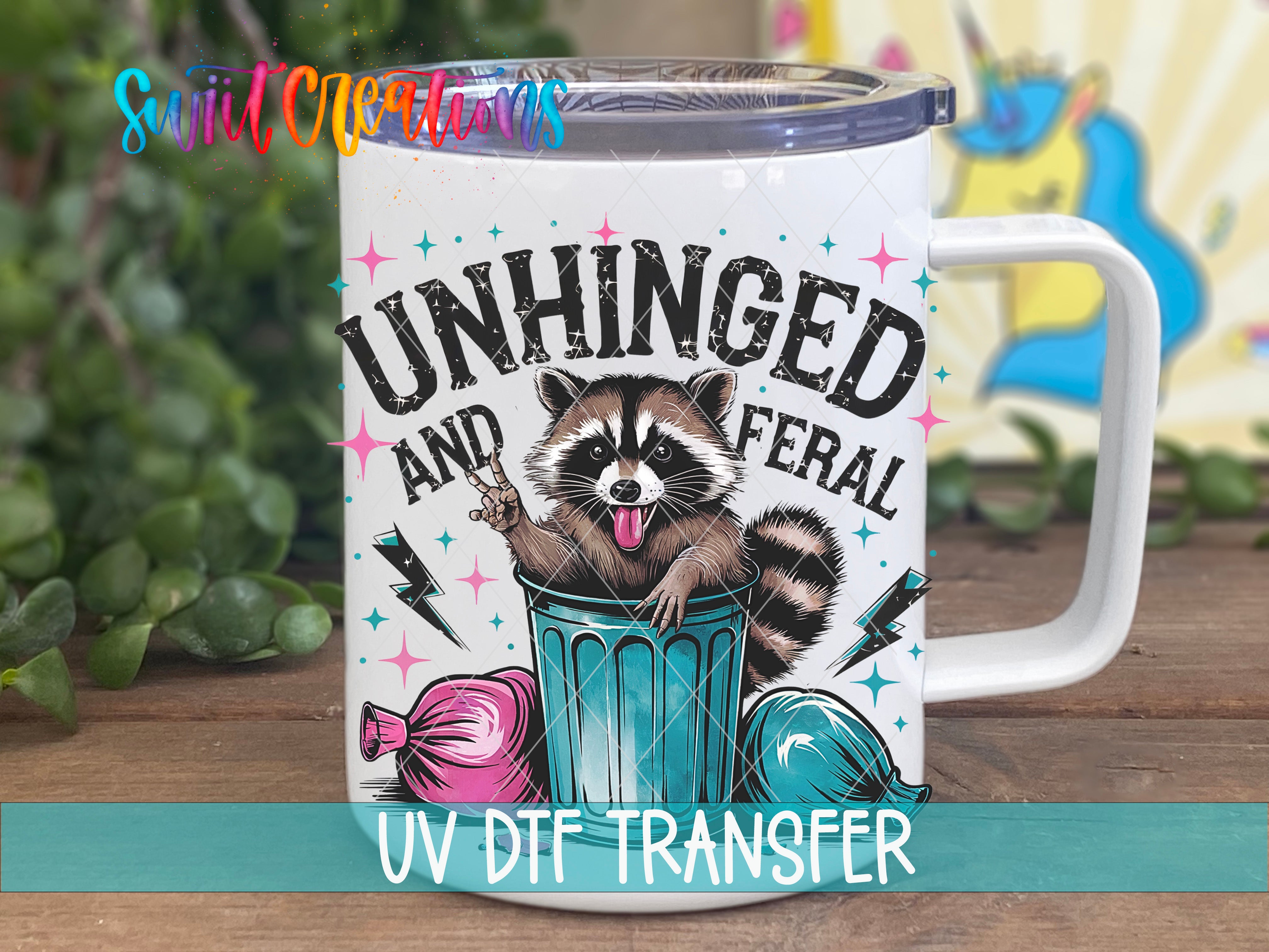 A mug with a raccoon sitting in a trash can, surrounded by various objects, and the text "UNHINGED AND FERAL" printed on it.