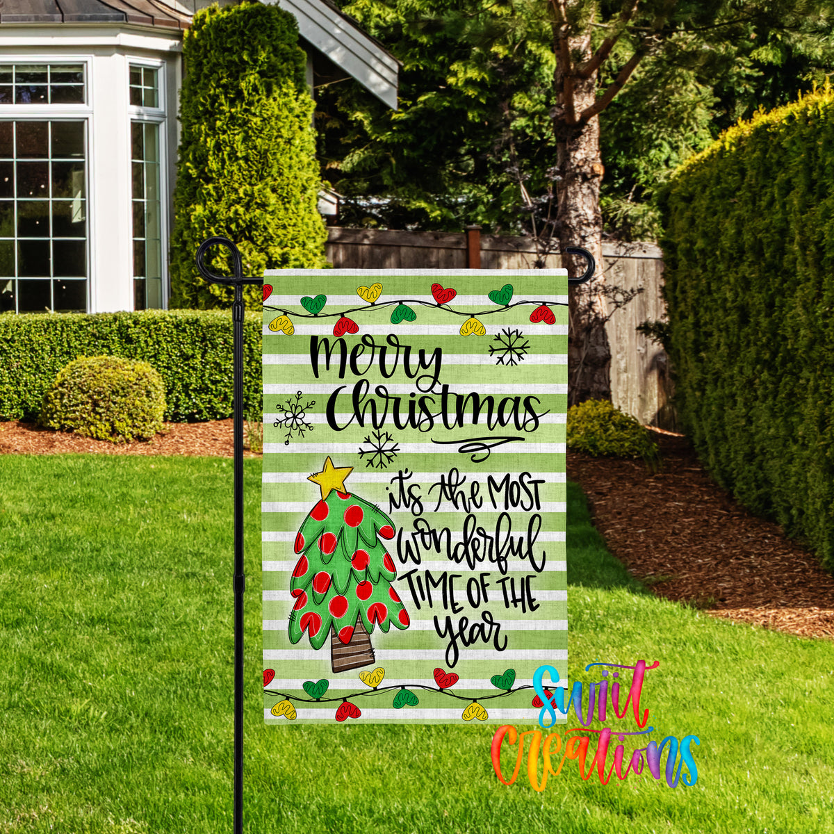 A festive Christmas-themed garden sign with a colorful design and text, placed in a well-maintained yard with a house and trees in the background.