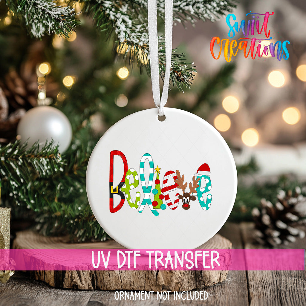 A white ornament with the word "Believe" written on it, hanging on a Christmas tree.