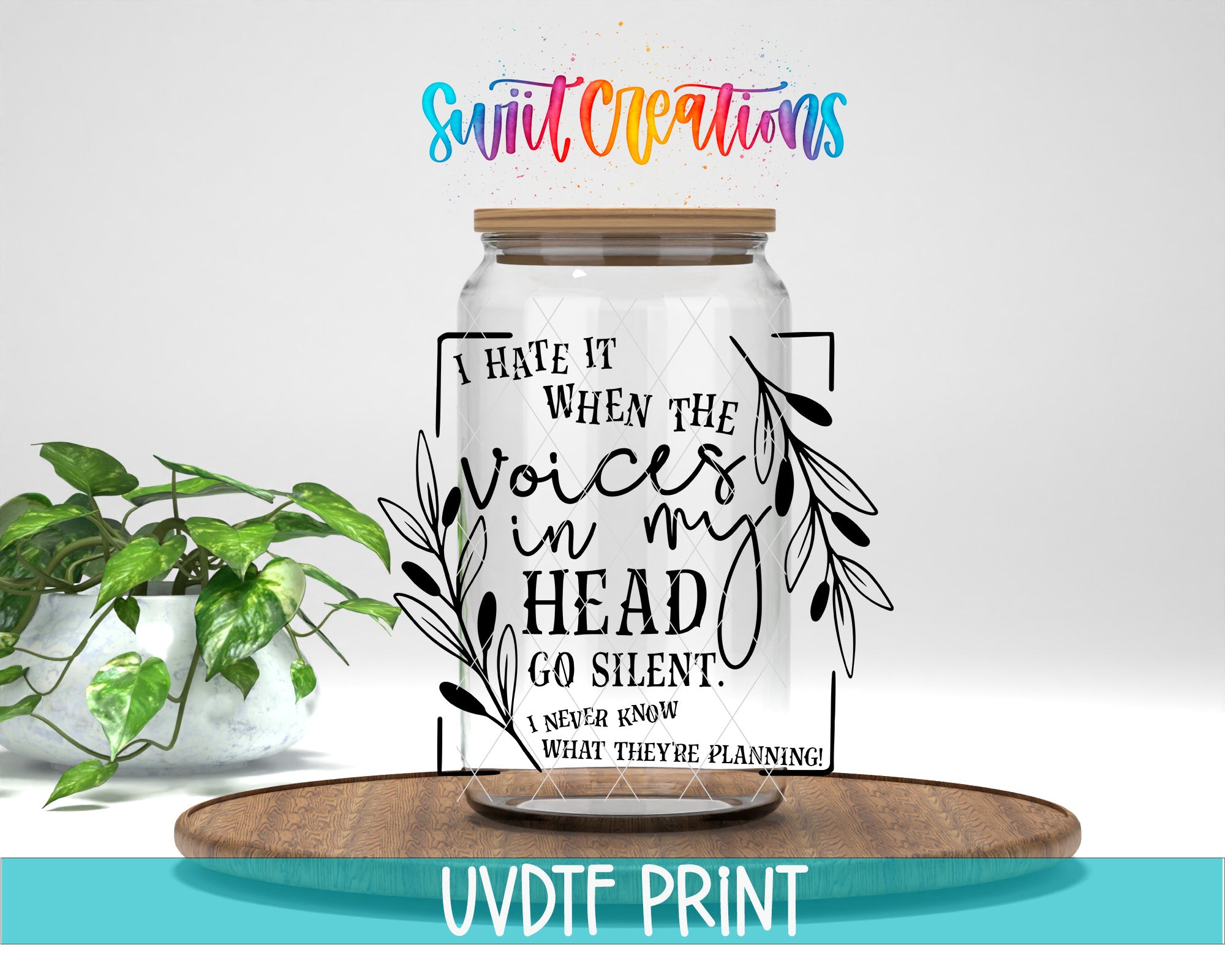 a clear glass jar with a wooden lid, placed on a wooden tray. The jar has a quote printed on it in a stylized font, and there is a plant in the background.