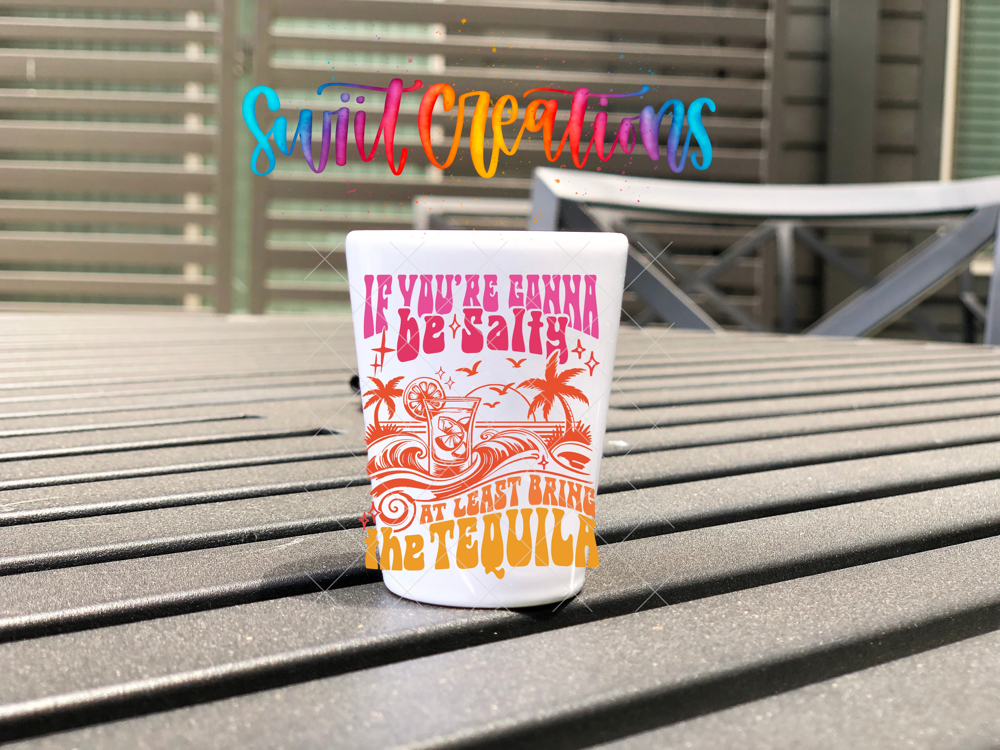 A white cup with a colorful design and text on it, placed on a wooden surface.