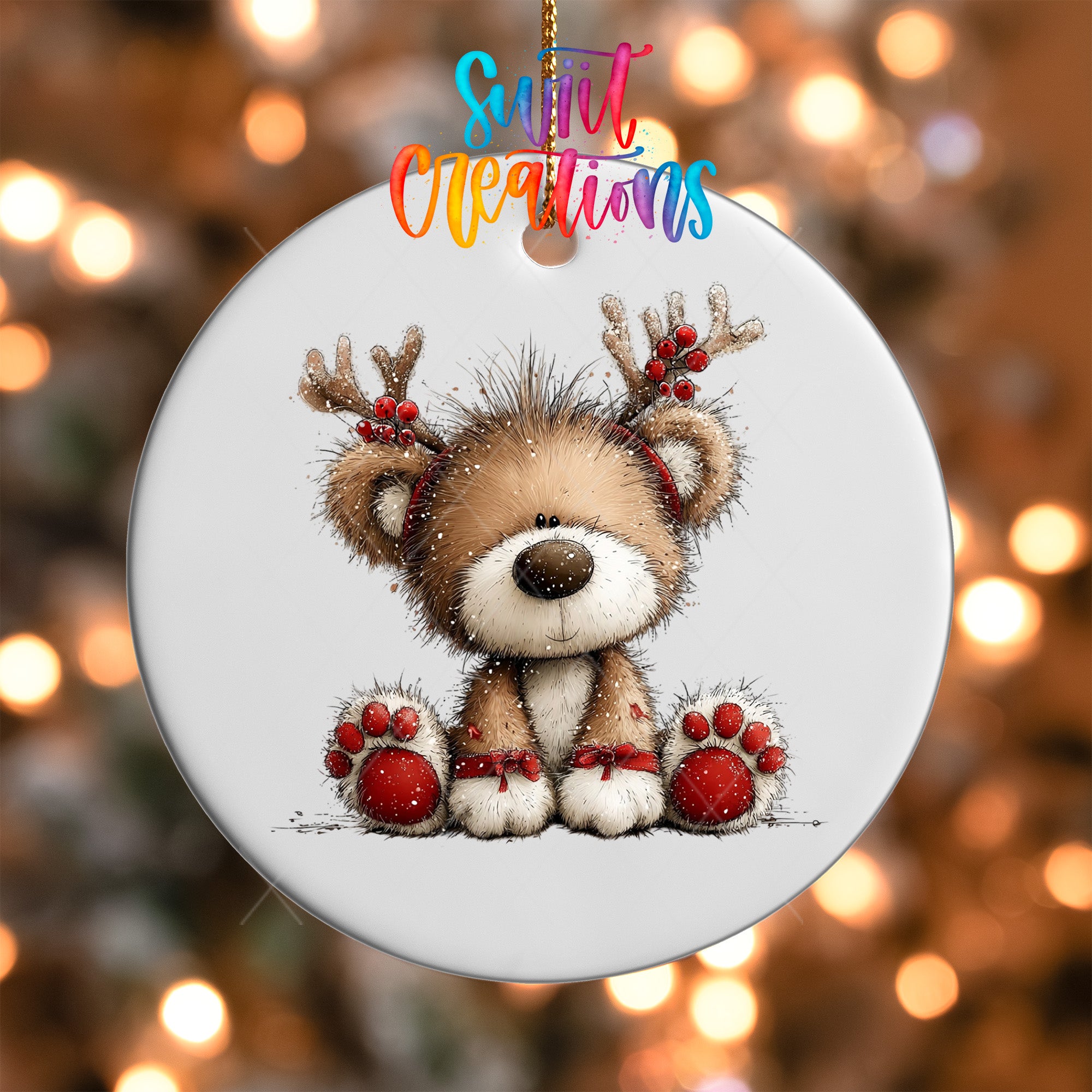 A white ornament with a cute brown bear wearing antlers and red boots, set against a blurred background with twinkling lights.