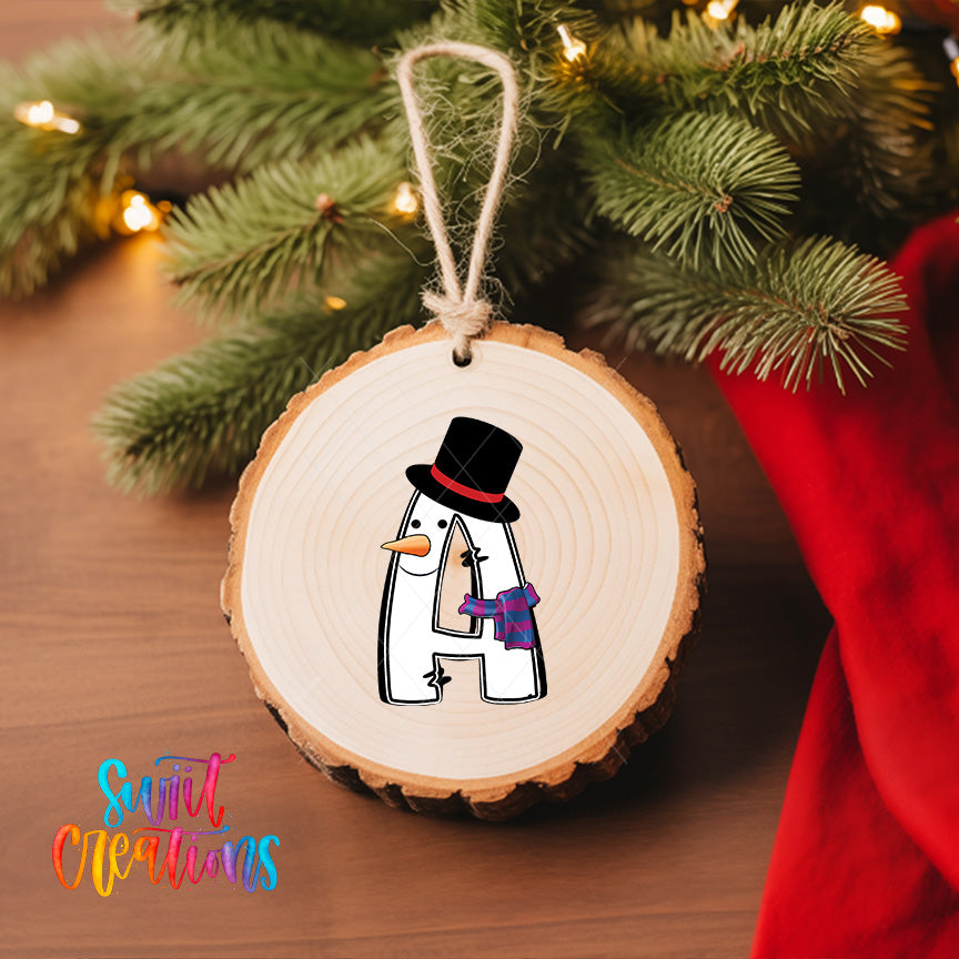 A wooden ornament with a snowman figure is hanging on a Christmas tree, surrounded by pine branches and twinkling lights.