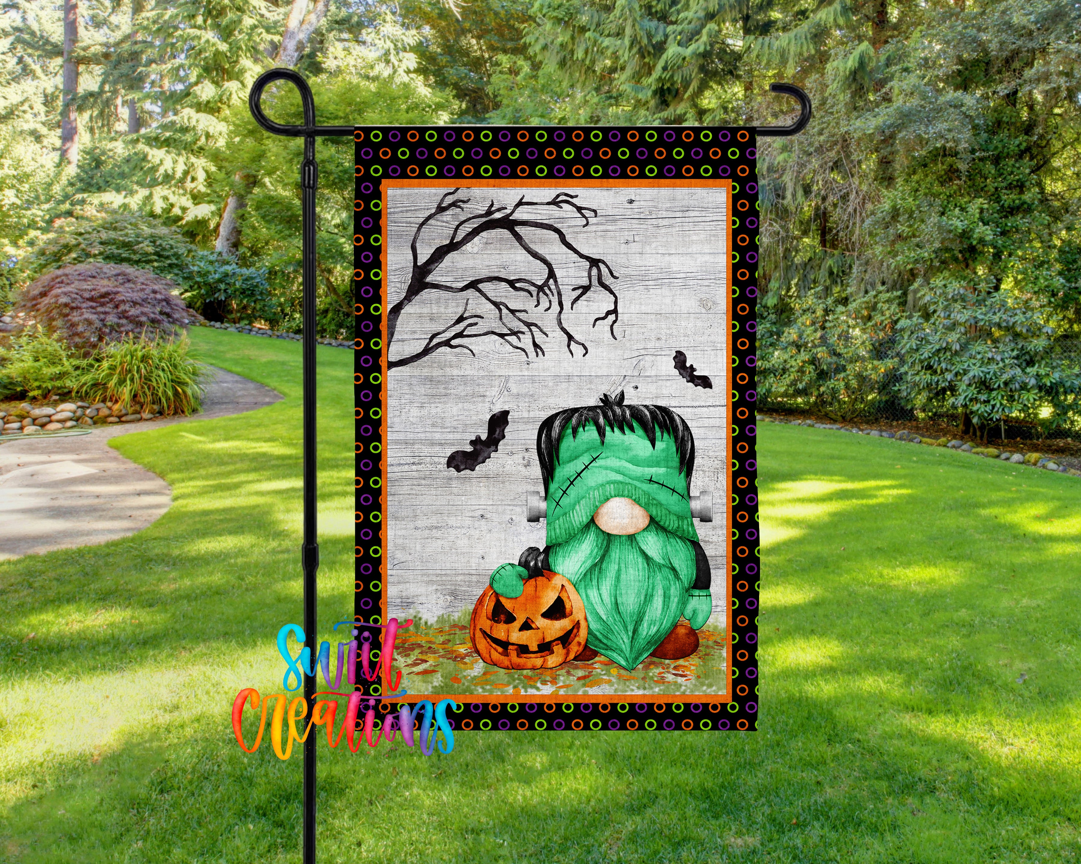 A Halloween-themed garden flag featuring a green gnome holding a jack-o-lantern, with a spooky tree and bats in the background.