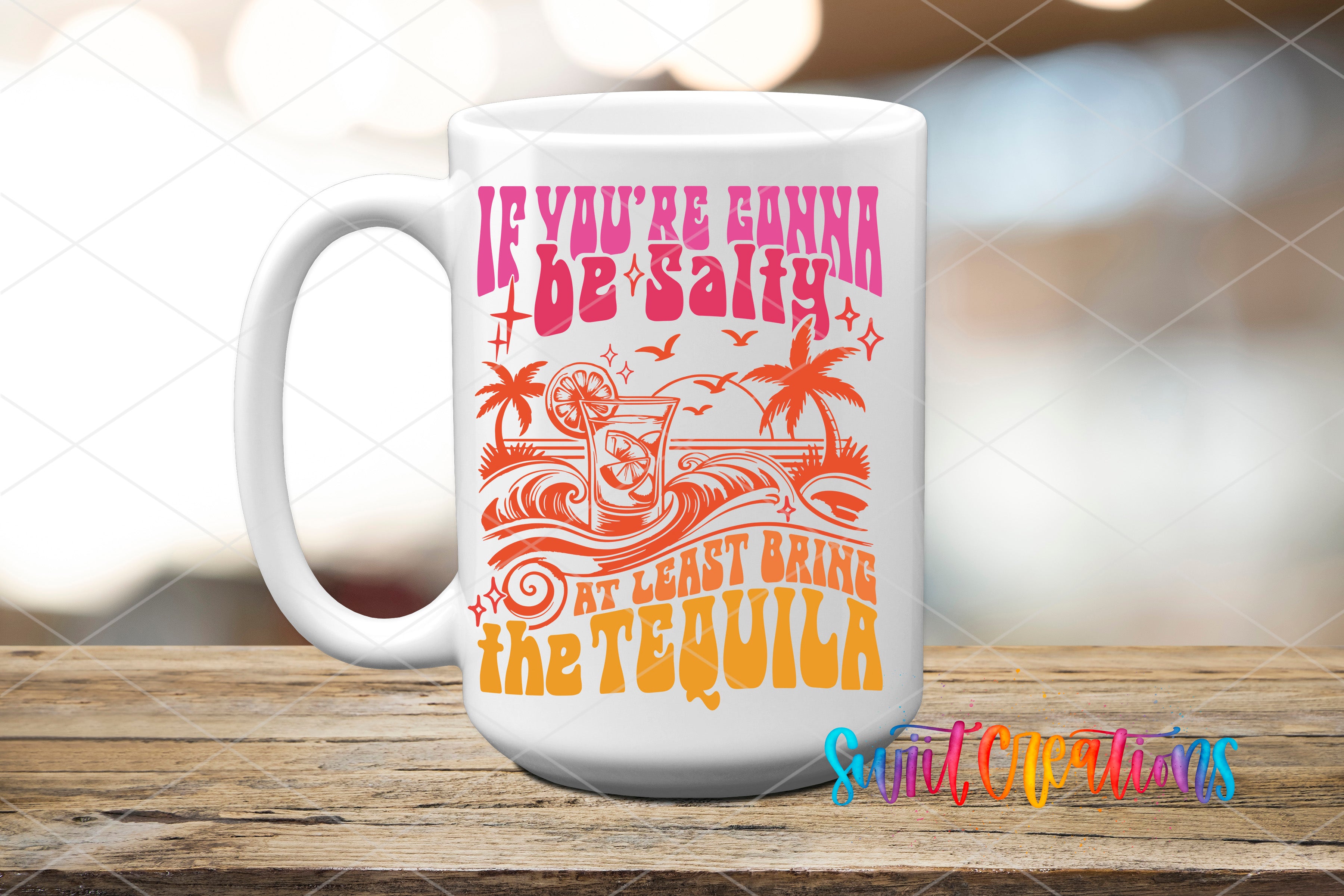 A white mug with a colorful graphic design featuring a beach scene and text that reads "If you're gonna be salty, at least bring the tequila".